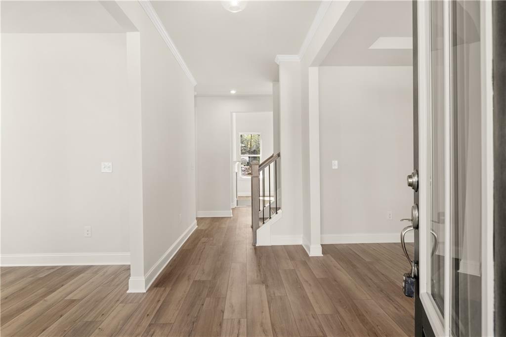 Bright entry foyer with hardwood floors, curved metal staircase, and glass front door in The Danbury C home, Buford, GA