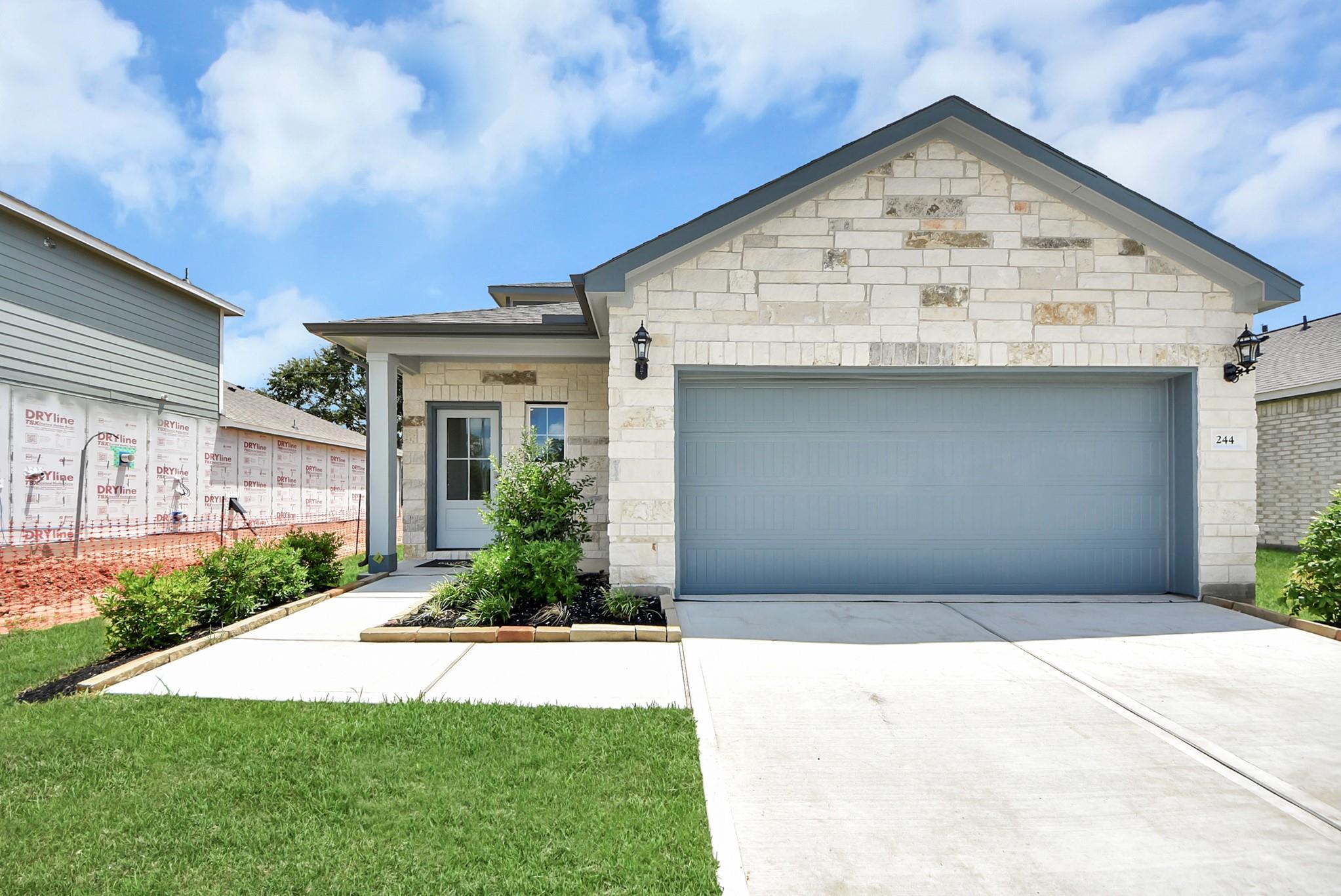 Stone-front exterior of The Sabine E floor plan with a 2-car garage in Windmill Estates, Magnolia, Texas.