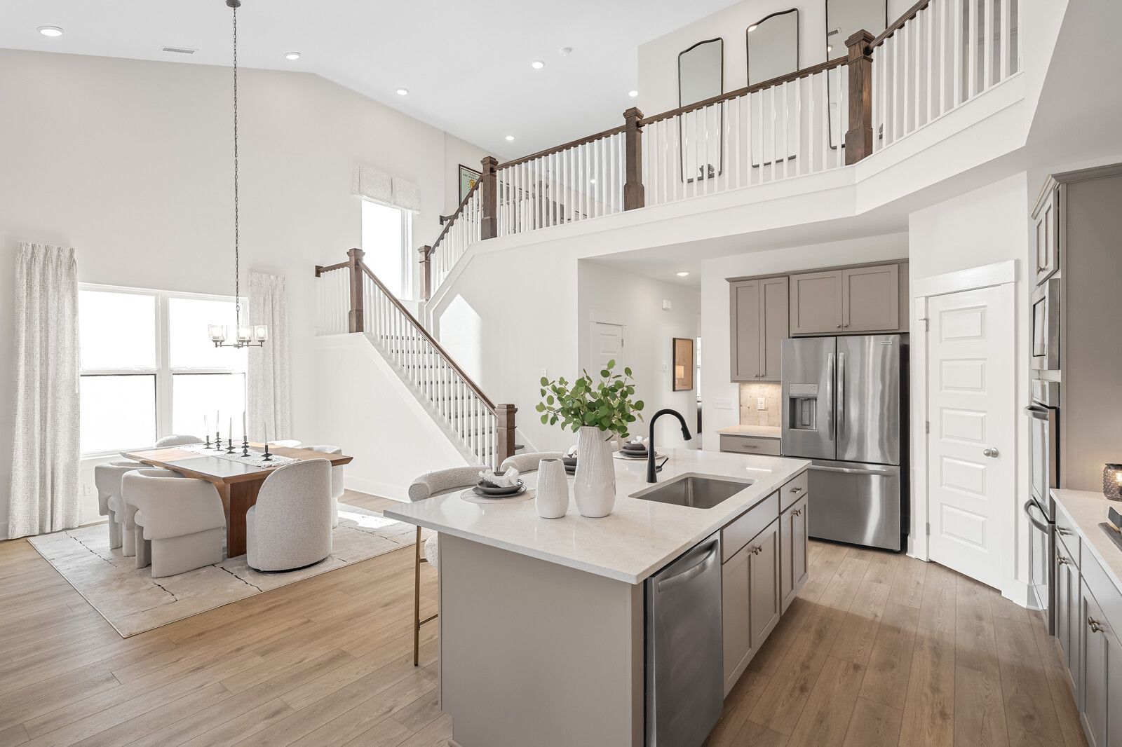 Open-concept kitchen and dining in Benders Cove, Mt. Juliet, TN with hardwood floors, large island, stainless appliances, and wooden staircase