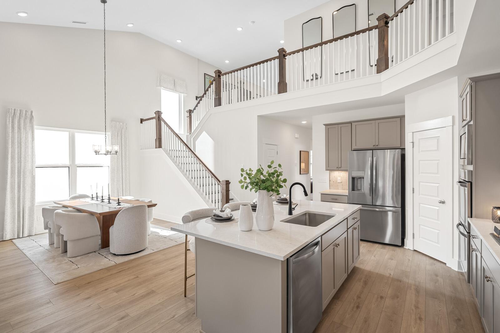 Open-concept kitchen and dining in Benders Cove, Mt. Juliet, TN with hardwood floors, large island, stainless appliances, and wooden staircase