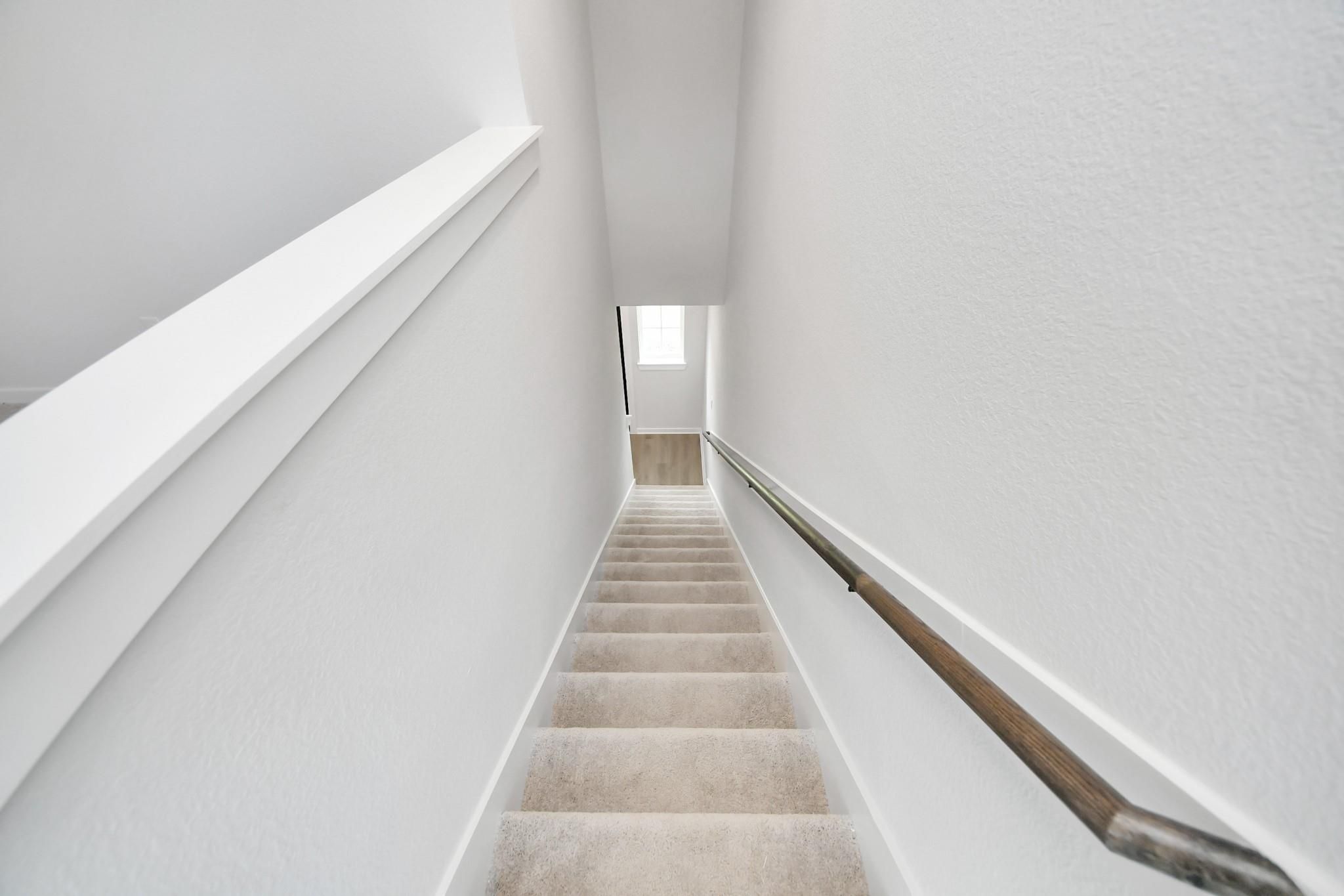 Carpeted staircase with modern handrail in The Blanco E floor plan at Caney Creek Place, Conroe, Texas.