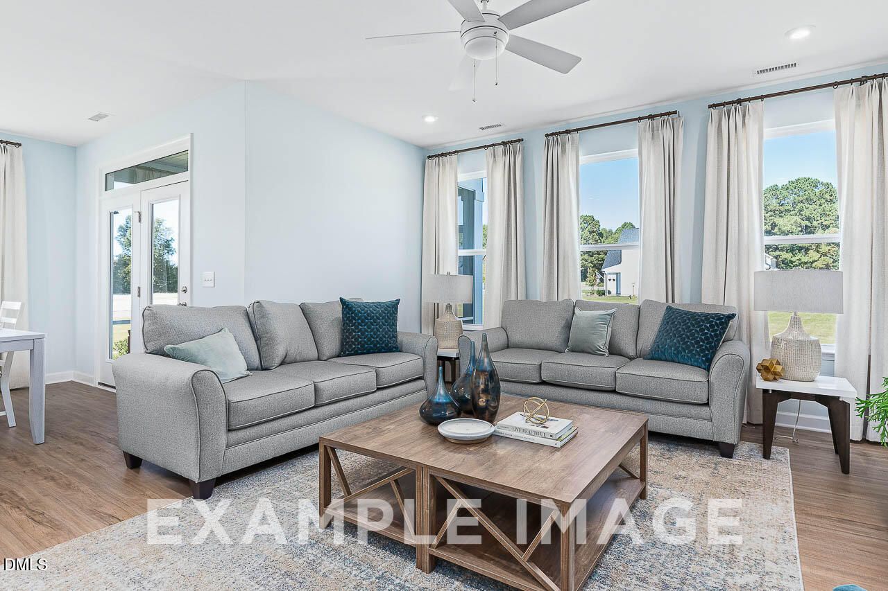 Bright living room with gray sofas, wood coffee table, and large windows in Davidson Homes The Ash C plan, Lillington NC