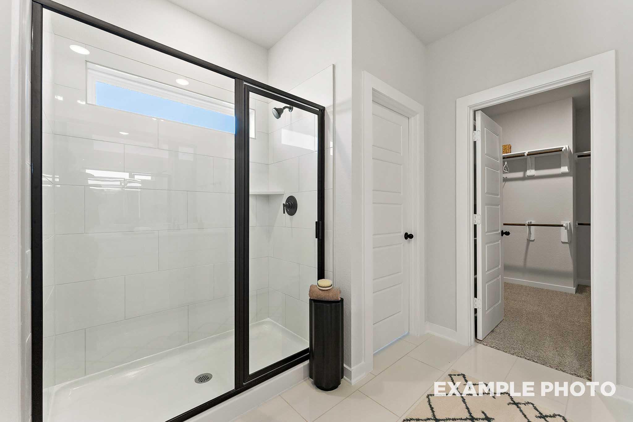 Modern walk-in shower with black frame and closet access in The Everett E floor plan at Sundance Cove, Crosby, Texas.