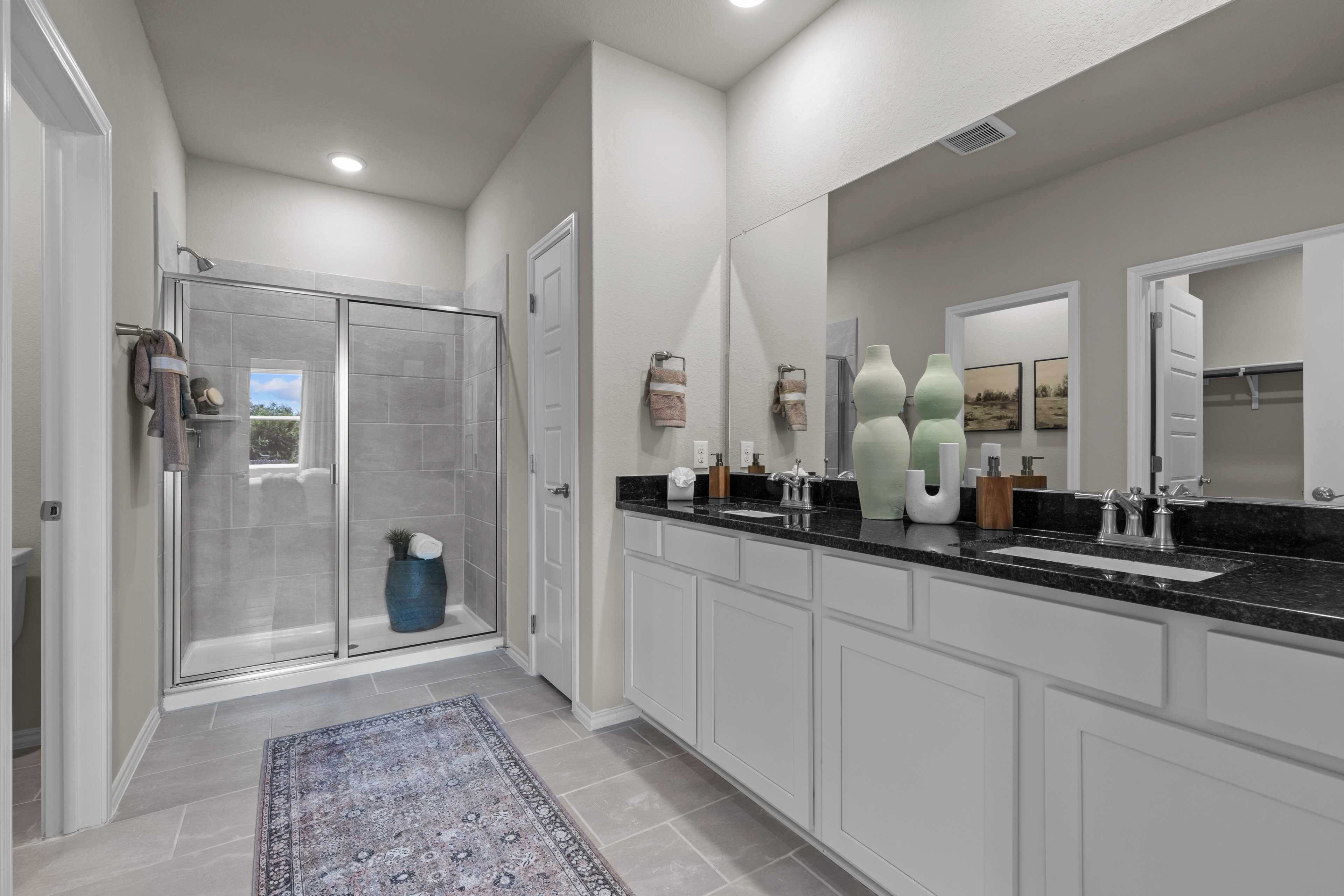 Spacious master bathroom at Comanche Ridge in San Antonio TX with glass shower, double vanity, and neutral tones