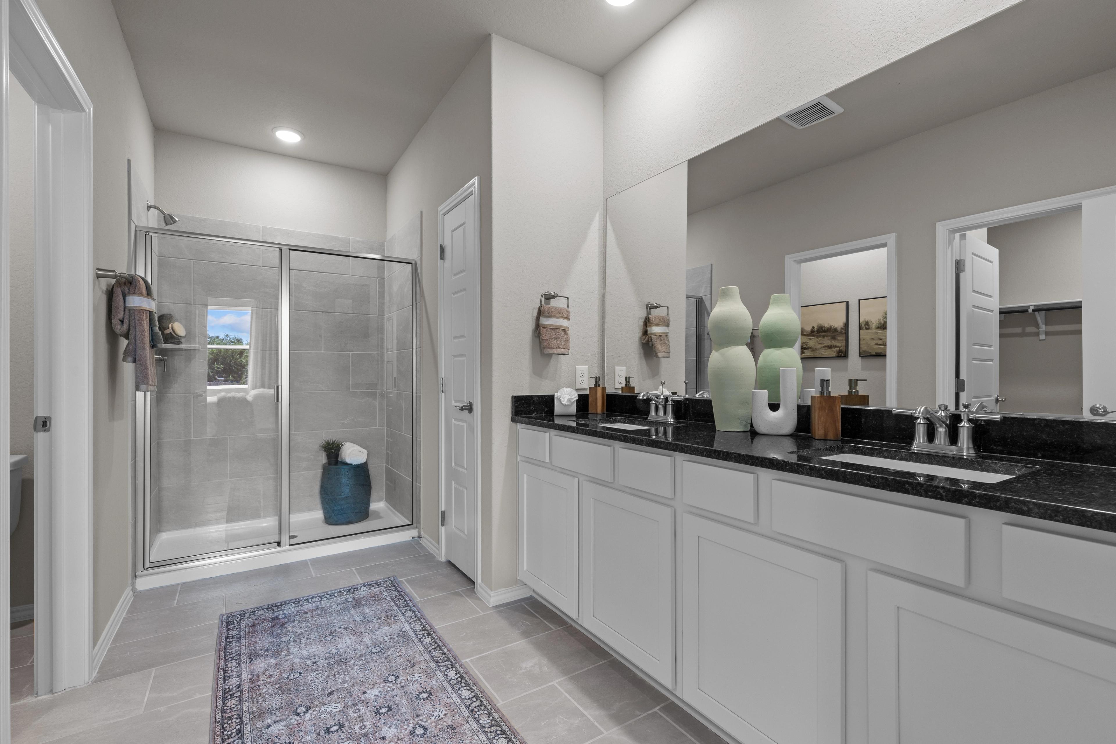 Spacious master bathroom at Comanche Ridge in San Antonio TX with glass shower, double vanity, and neutral tones