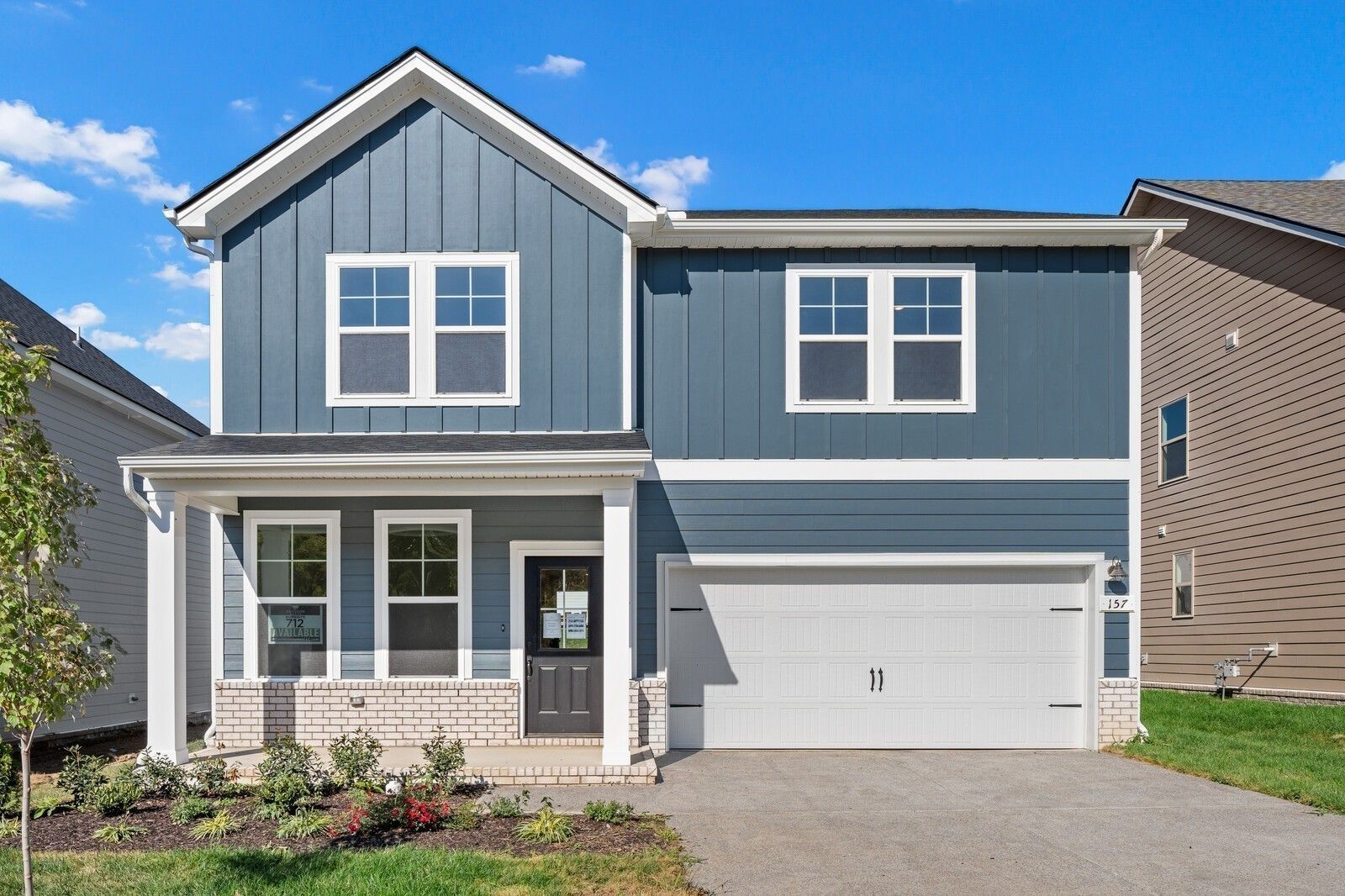 Modern two-story blue home with board-and-batten siding, covered front porch, two-car garage in Woods Crossing, Gallatin, Tennessee - Davidson Homes The Logan C