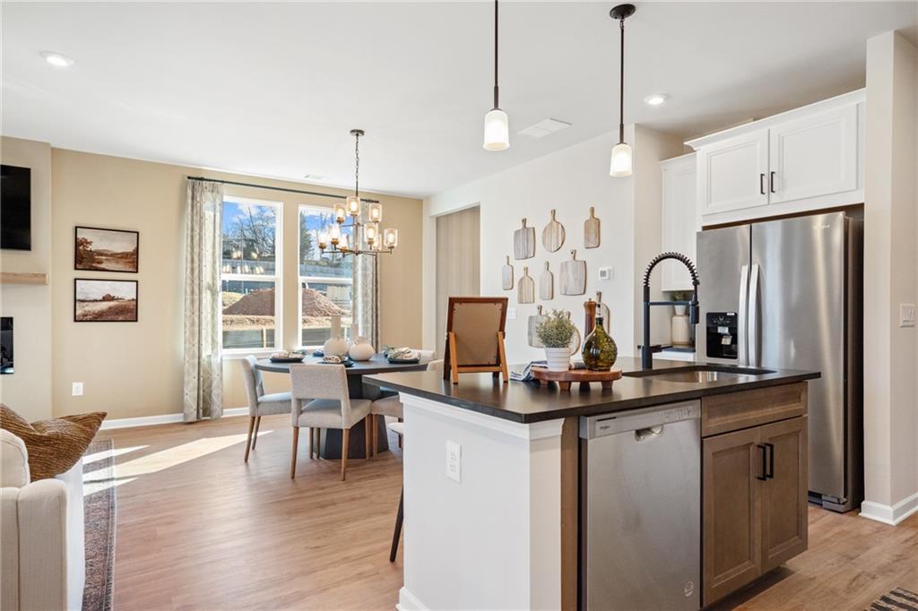 Open-concept kitchen with black granite island, stainless appliances, white cabinets, and dining nook in Davidson Homes The Marion B, Kennesaw, Georgia