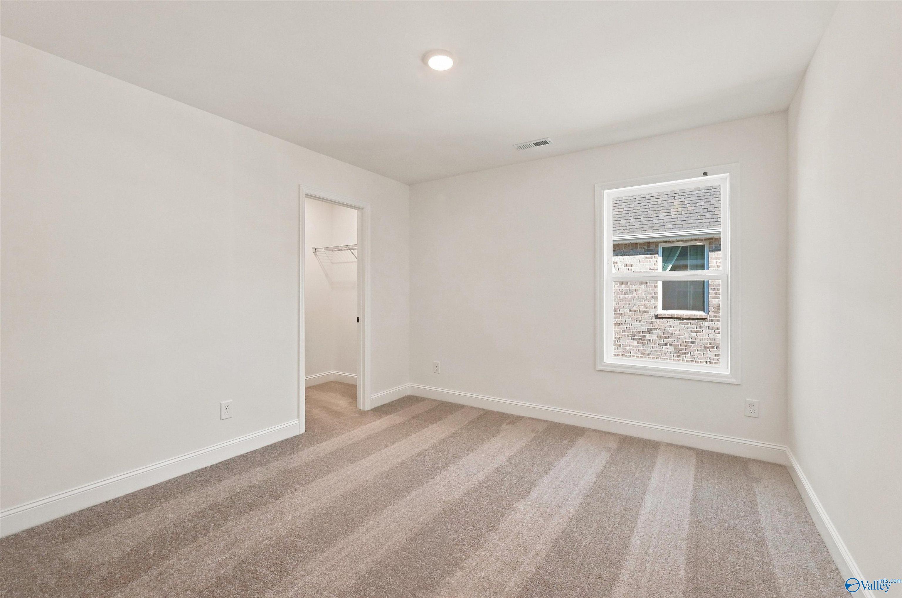 Bright bedroom with plush carpet and walk-in closet in The Chelsea C floor plan at Creek Grove, New Market, Alabama.