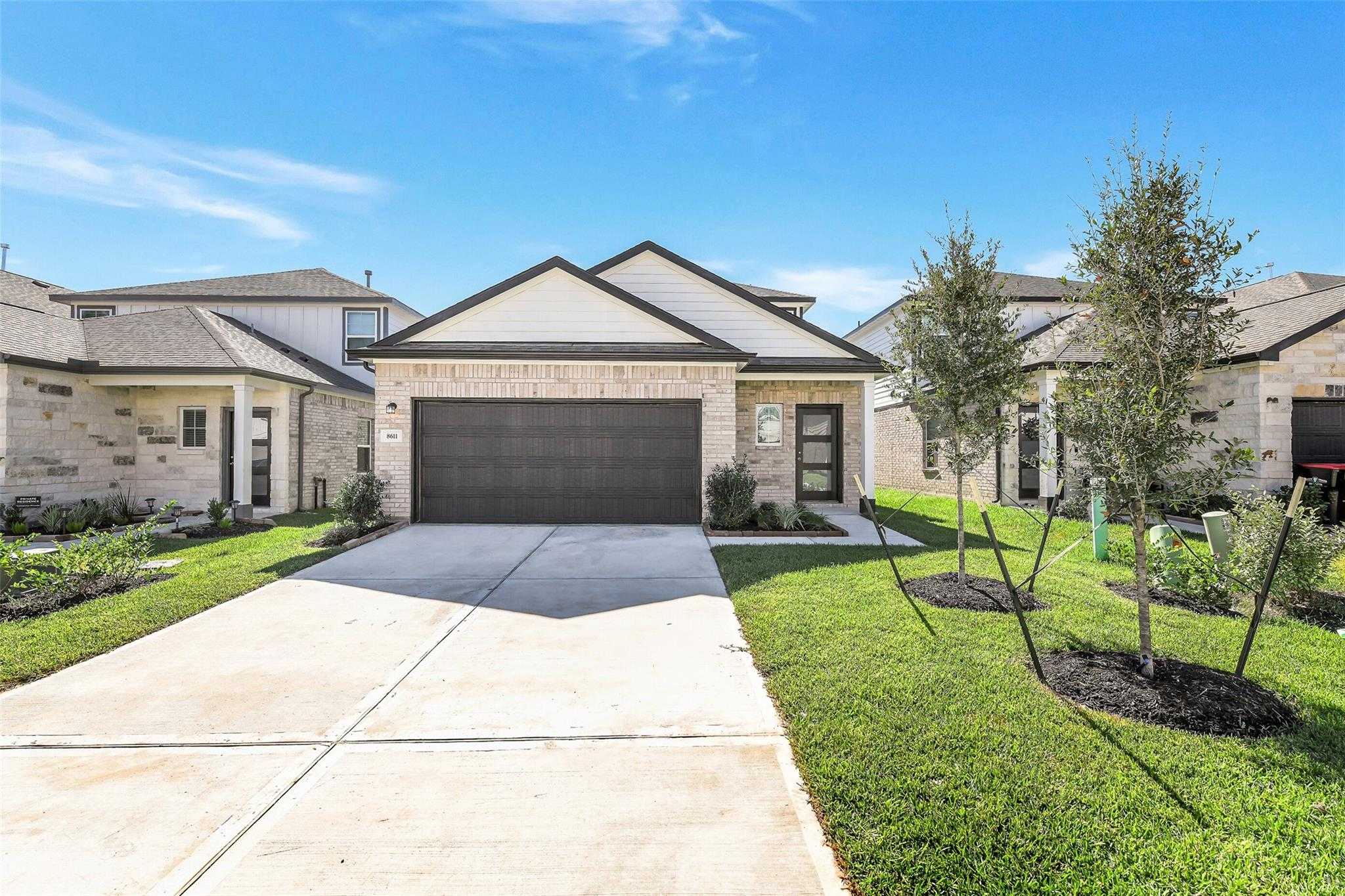 Modern two-story brick home with two-car garage, driveway, and landscaped yard in Lakes at Black Oak, Magnolia, Texas