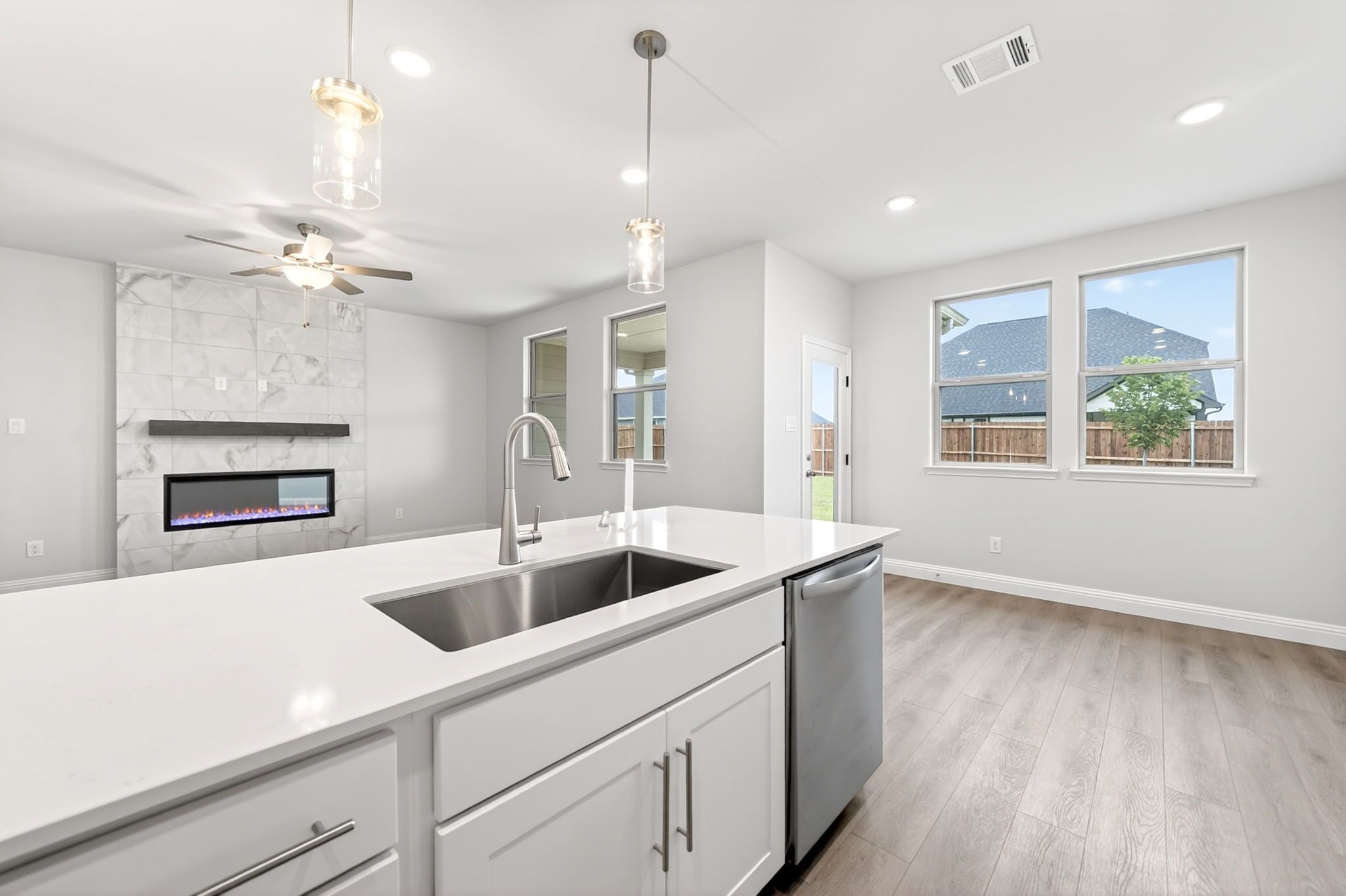 Open-concept kitchen and living area in The Redbud plan featuring a white island, modern fireplace, and wood-style flooring.