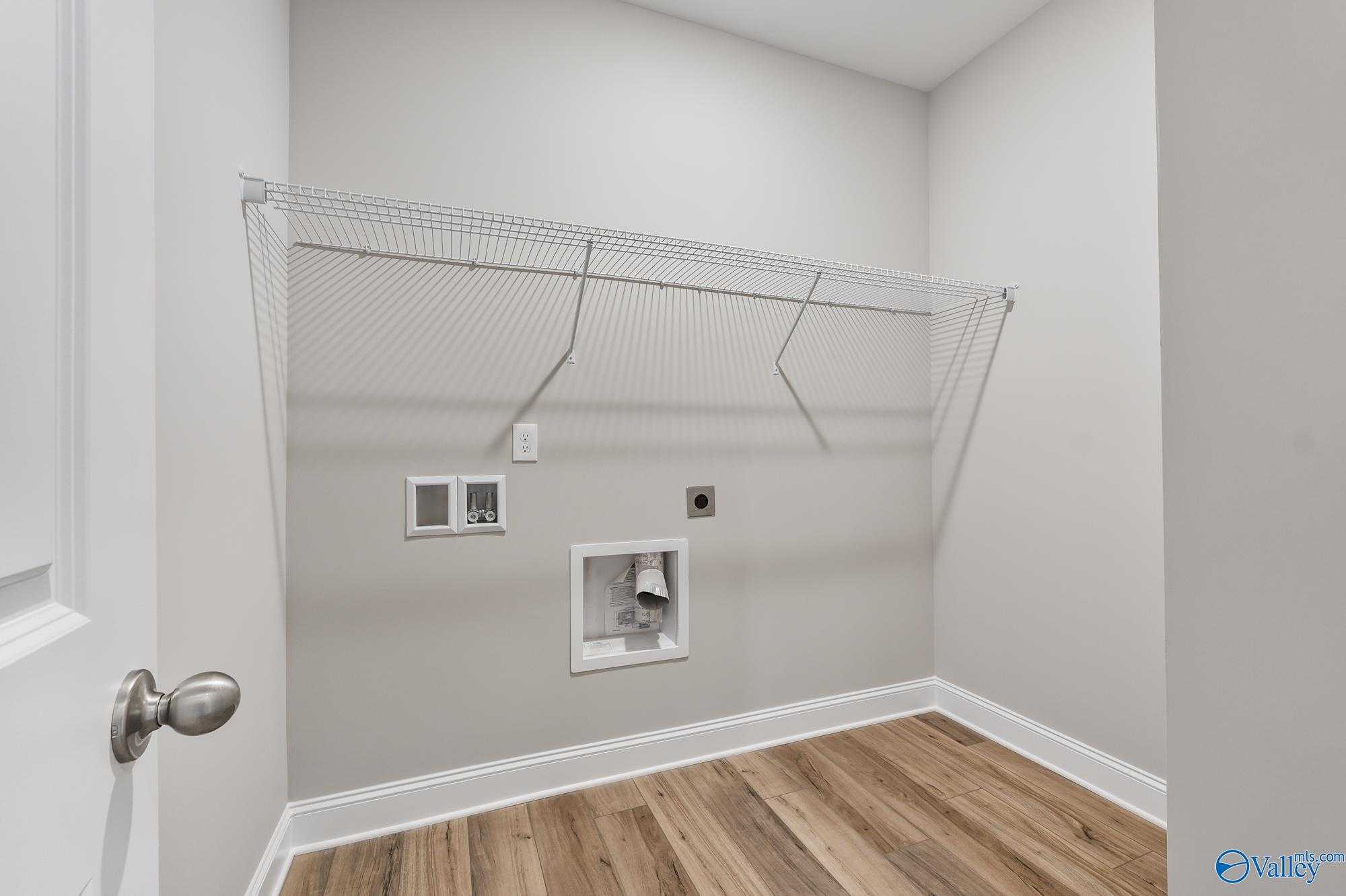 Spacious laundry room with washer dryer hookups, hanging rod and hardwood floors in Davidson Homes The Daphne D, Athens Alabama
