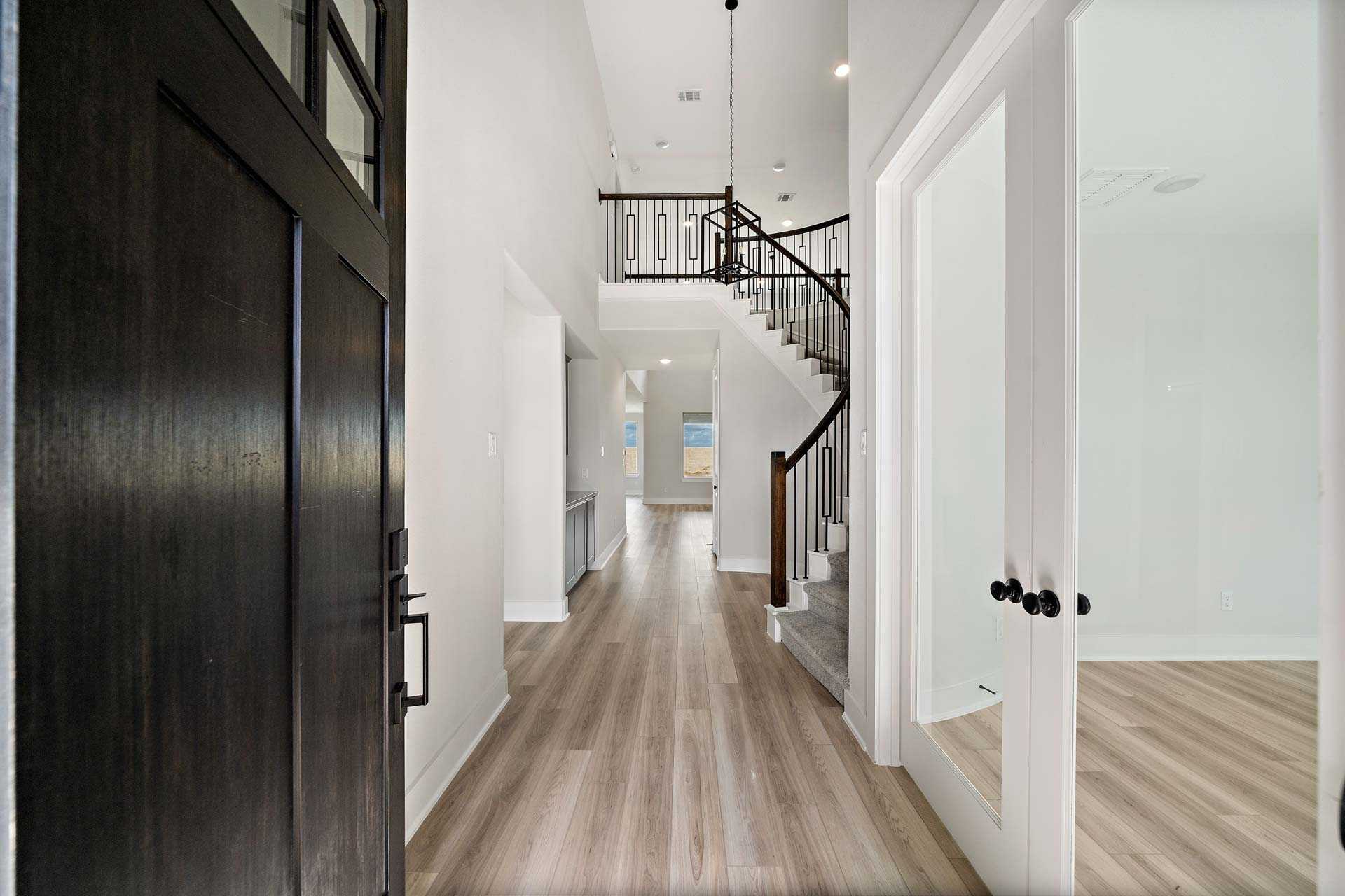 Spacious entryway at Sierra Vista in Rosharon Texas featuring dark wood door curved staircase light oak floors by Davidson Homes