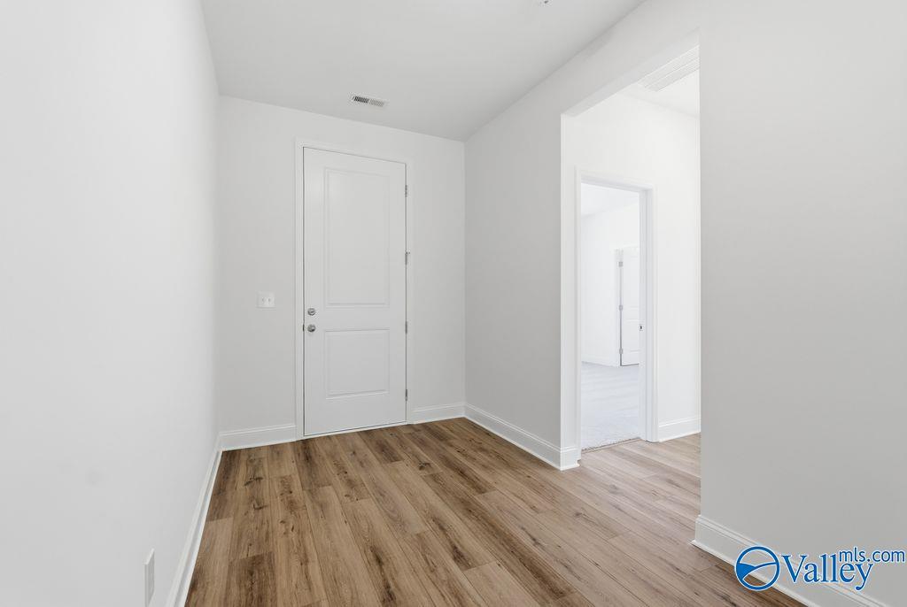 Bright hallway with white doors, open archway, and luxury vinyl plank flooring in Davidson Homes The Montgomery, Hartselle, Alabama