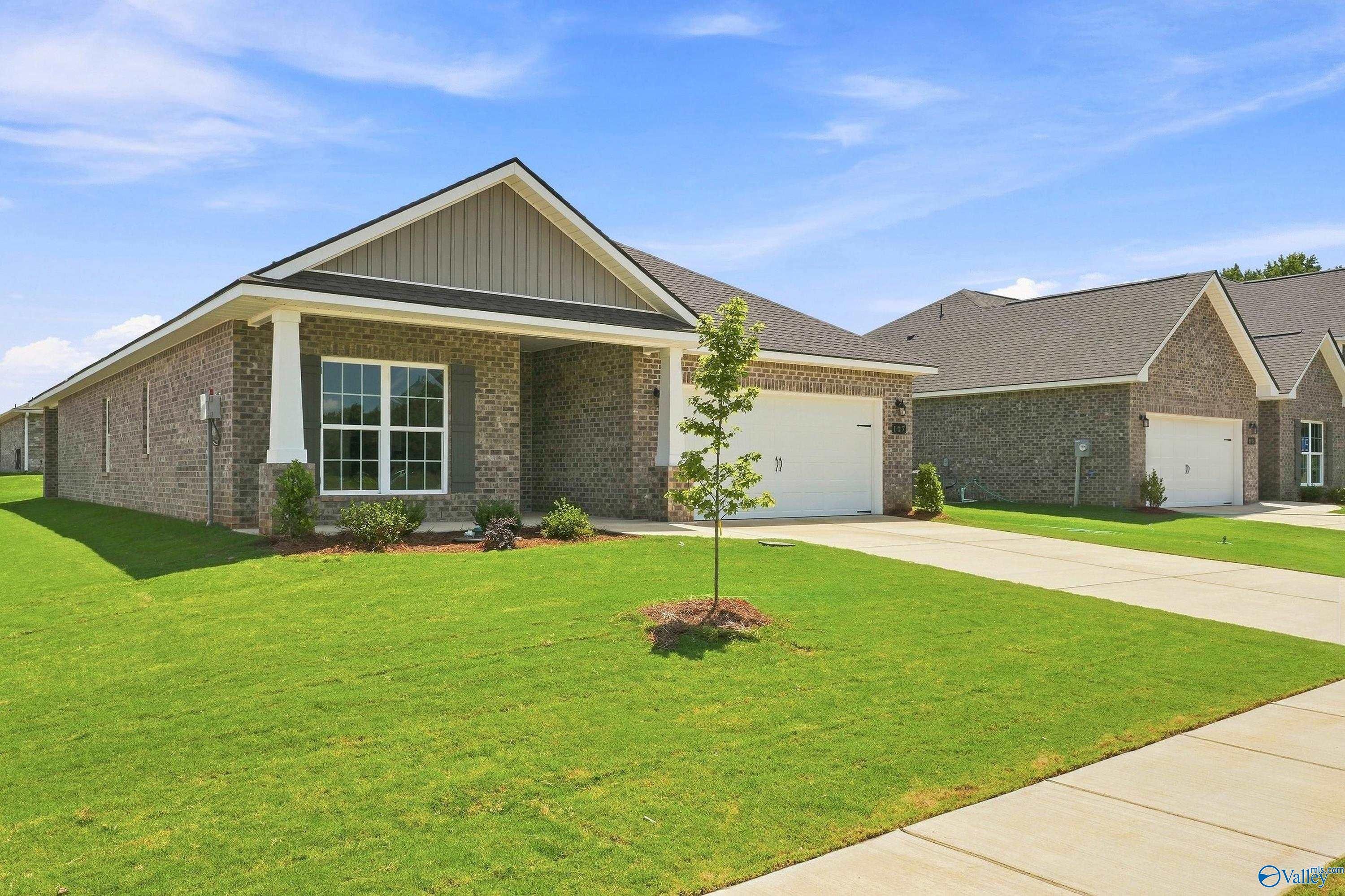 Brick front exterior with covered porch and 2-car garage of Davidson Homes The Everett B in Wood Trail, Toney, Alabama