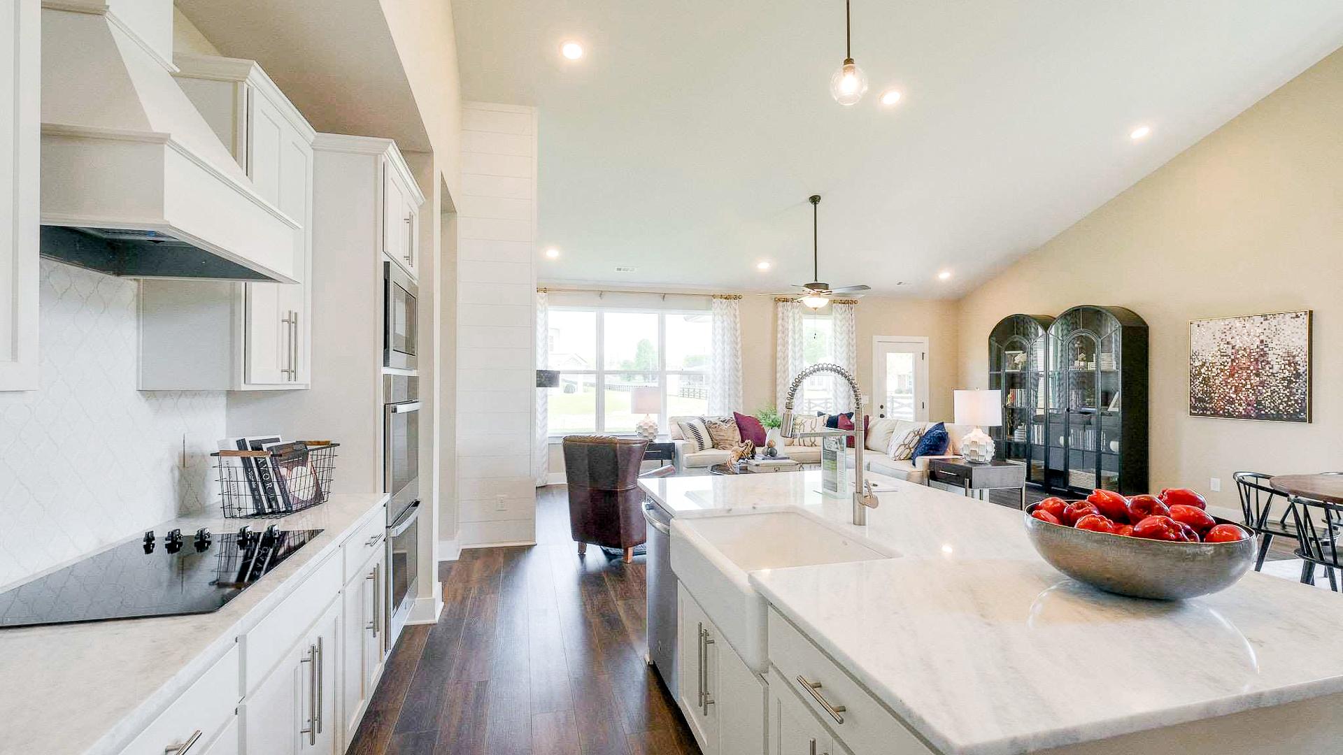 Open-concept kitchen at The Meadows in Smyrna TN with white shaker cabinets, marble island, stainless appliances, and adjacent living area