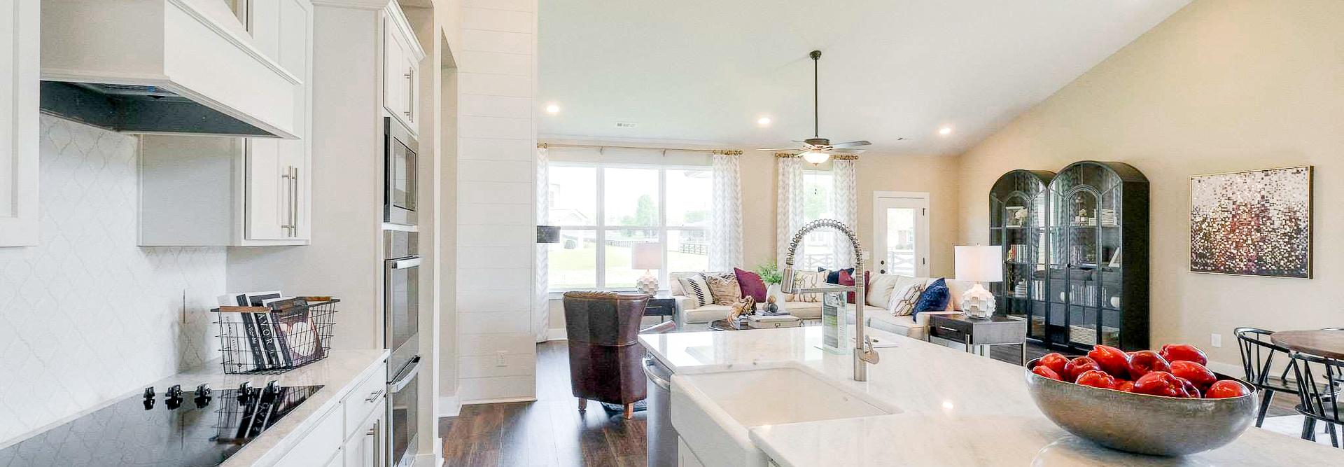 Open-concept kitchen at The Meadows in Smyrna TN with white shaker cabinets, marble island, stainless appliances, and adjacent living area