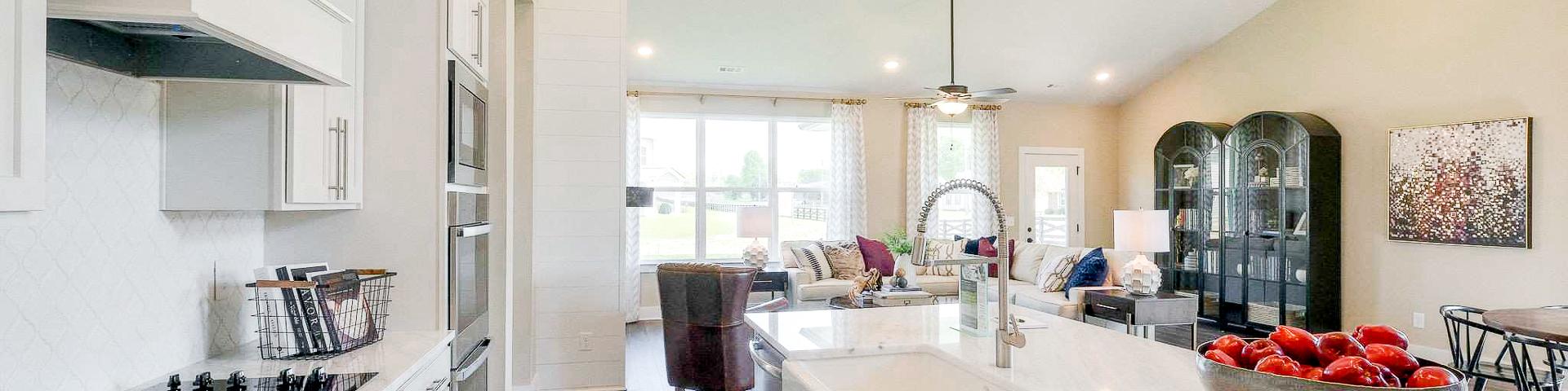 Open-concept kitchen at The Meadows in Smyrna TN with white shaker cabinets, marble island, stainless appliances, and adjacent living area