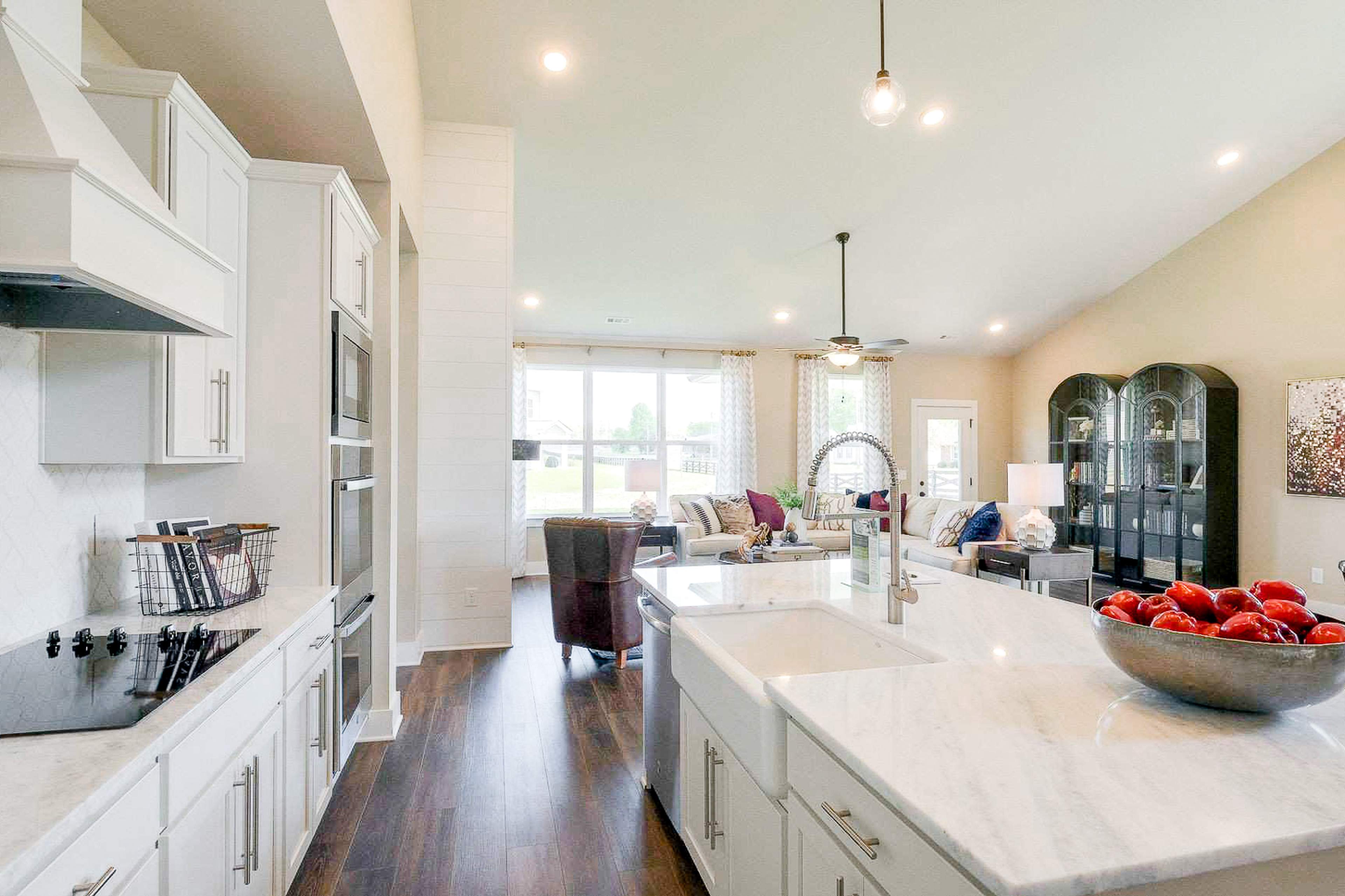 Open-concept kitchen at The Meadows in Smyrna TN with white shaker cabinets, marble island, stainless appliances, and adjacent living area