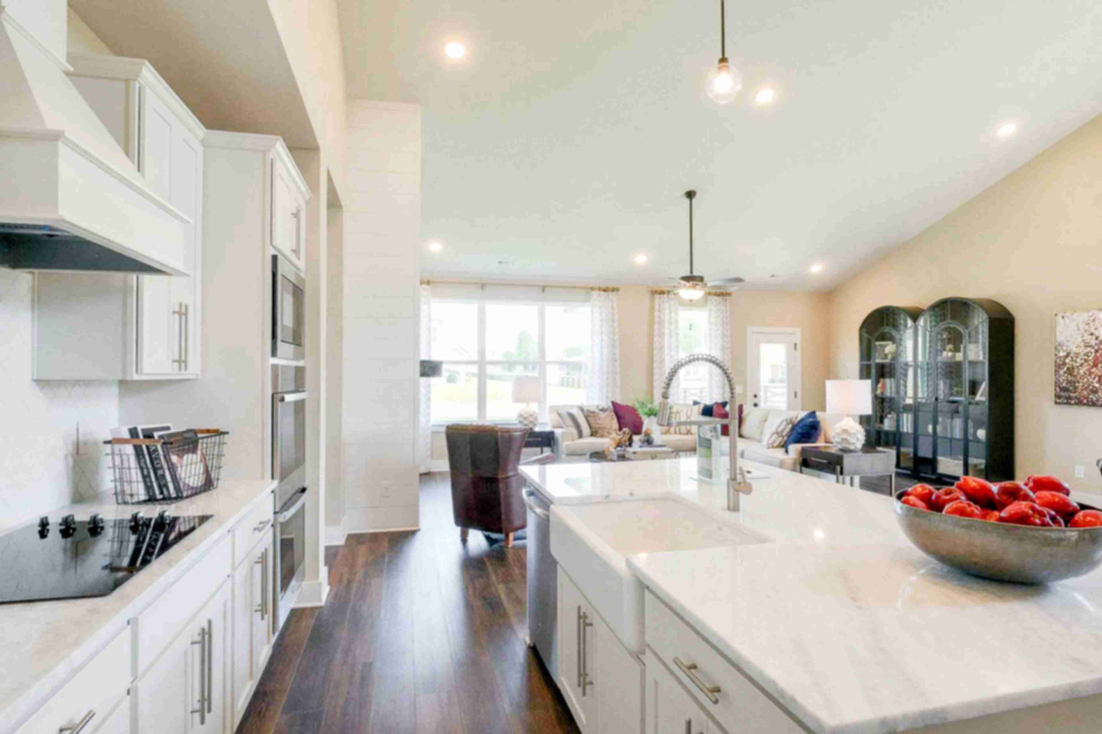 Open-concept kitchen at The Meadows in Smyrna TN with white shaker cabinets, marble island, stainless appliances, and adjacent living area