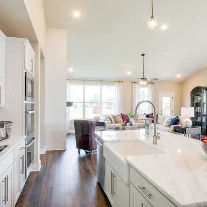 Open-concept kitchen at The Meadows in Smyrna TN with white shaker cabinets, marble island, stainless appliances, and adjacent living area