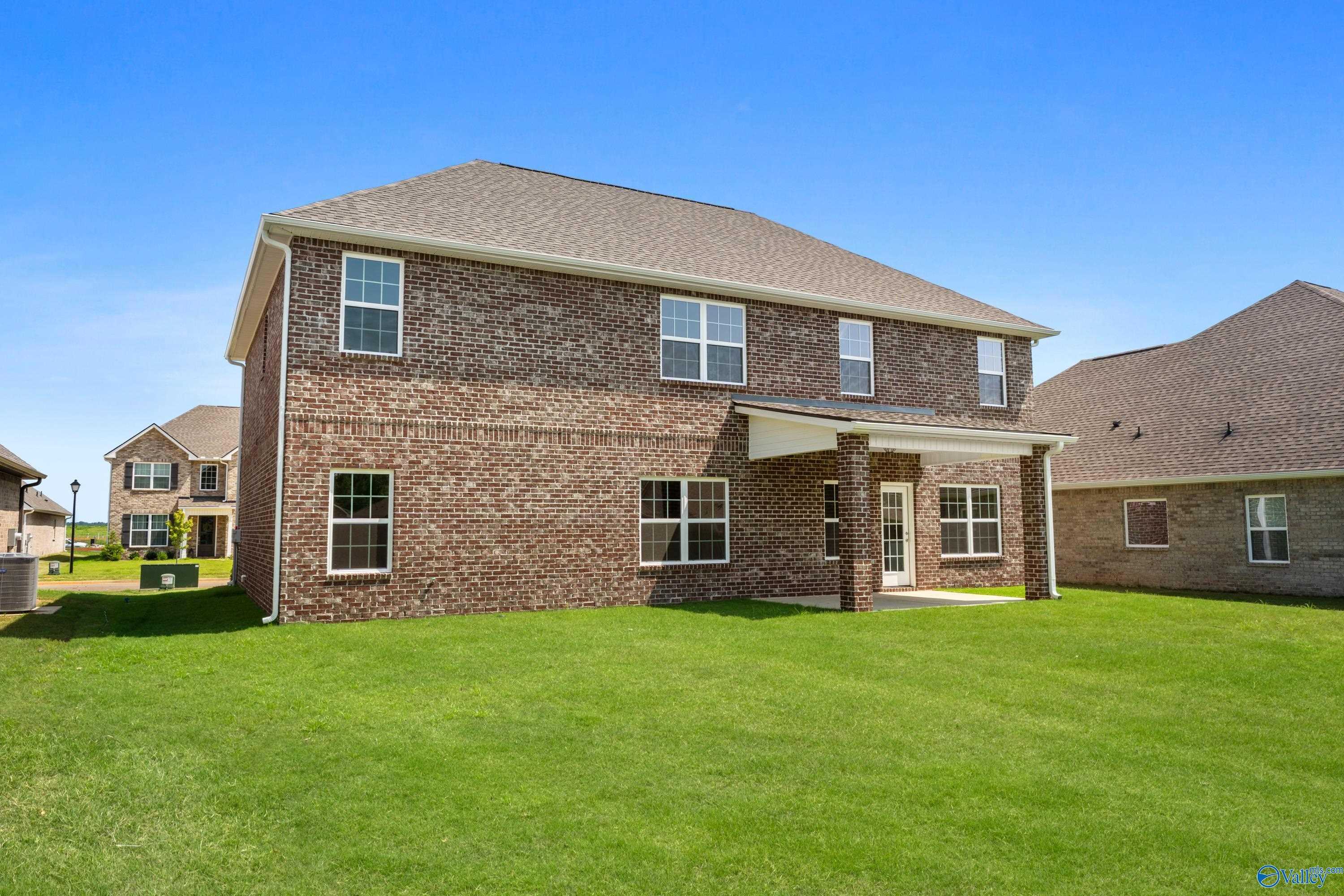 Two-story brick 5-bedroom home with garage and covered porch on lush lawn in Kendall Downs, Toney, Alabama
