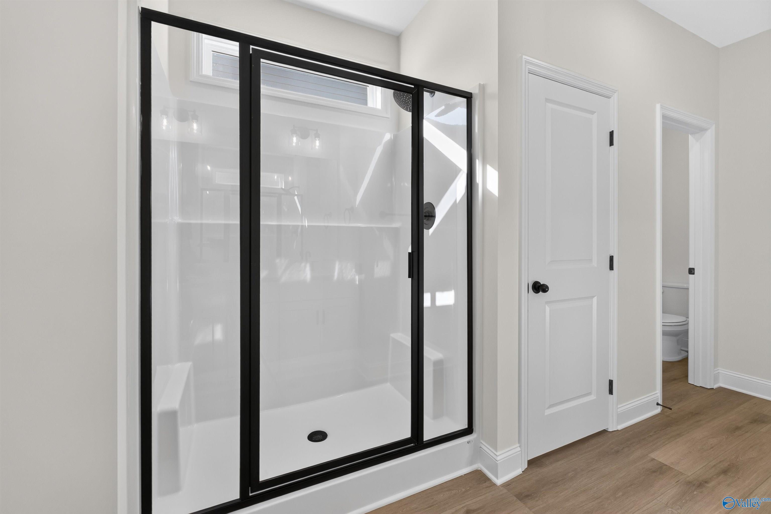 Black-framed glass walk-in shower with built-in bench in primary bathroom of Davidson Homes Ashport L plan, Berry Cove