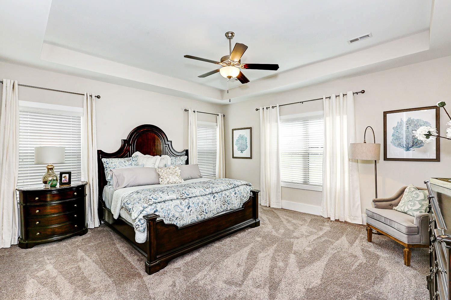 Spacious master bedroom in The Finleigh with king bed, floral bedding, ceiling fan, and large windows