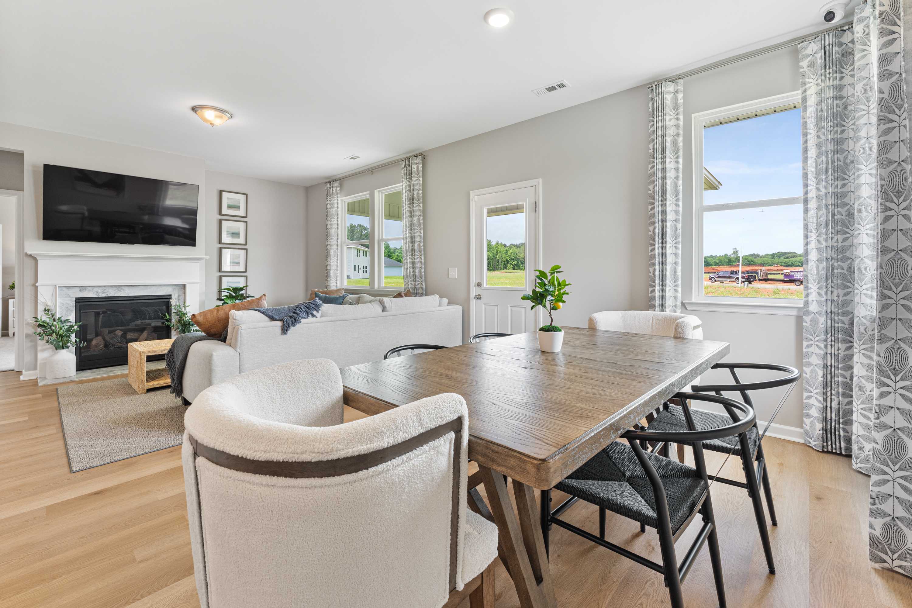 Open-concept living dining room in Forest Glen Hazel Green AL with white sofa fireplace TV hardwood floors and large windows