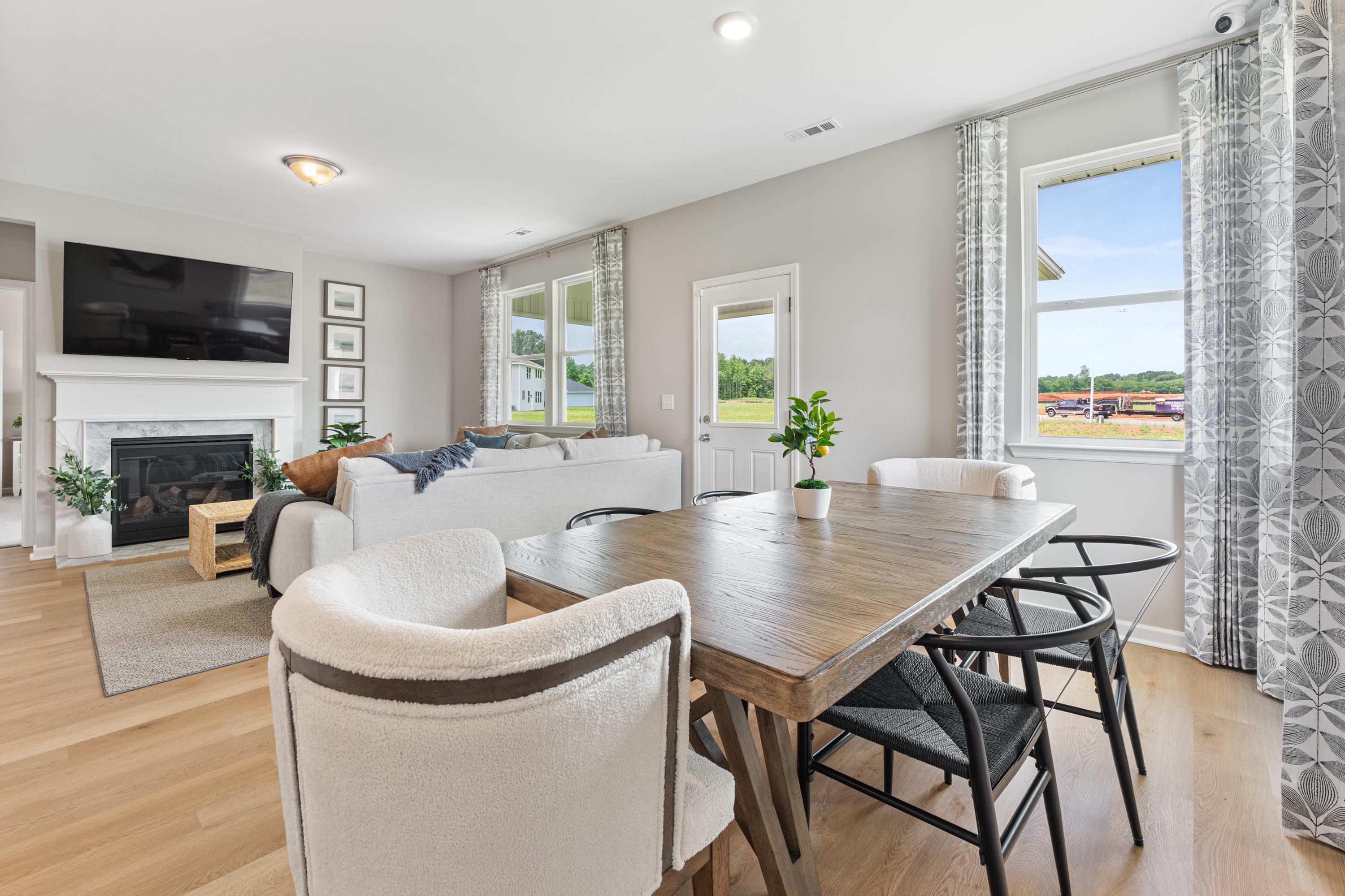 Open-concept living dining room in Forest Glen Hazel Green AL with white sofa fireplace TV hardwood floors and large windows