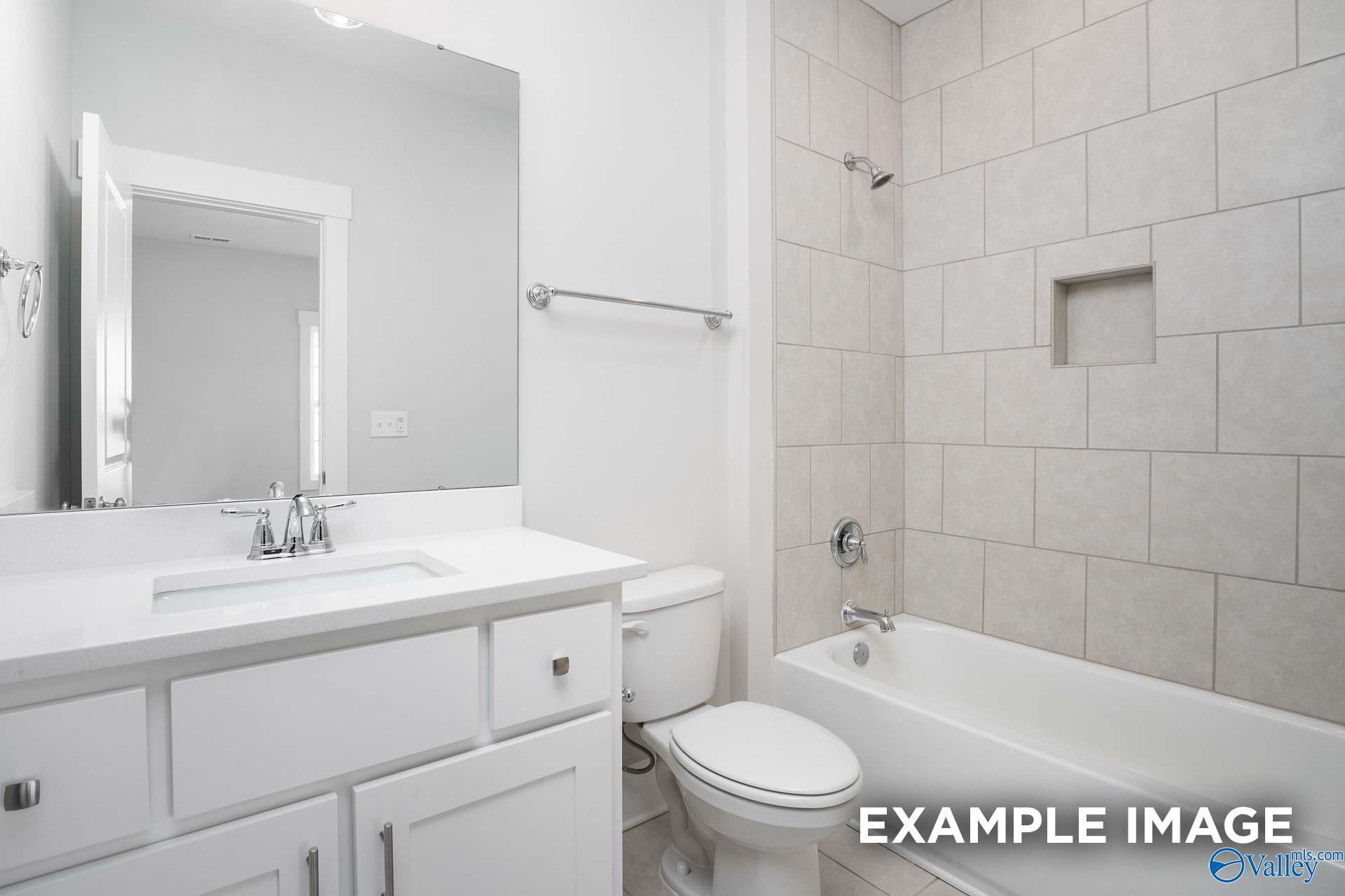Elegant secondary bathroom with white shaker vanity, tiled shower-tub combo in Davidson Homes The Harrison, Decatur AL