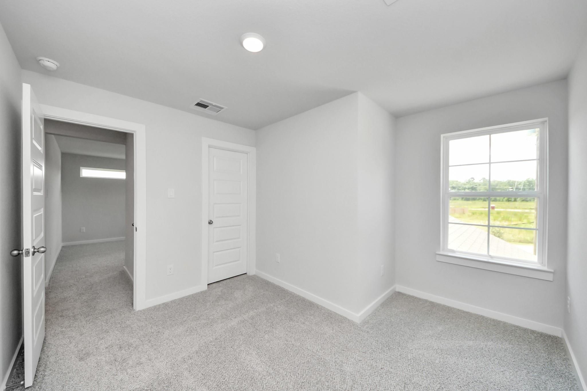 Bright, carpeted spare bedroom with closet in The Sabine F floor plan at Liberty Estates, Cleveland, Texas.