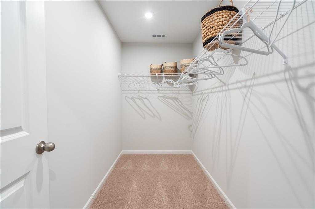 Spacious walk-in closet with wire shelving, hanging rods and wicker baskets in Davidson Homes The Wilmington B, Emerson, GA
