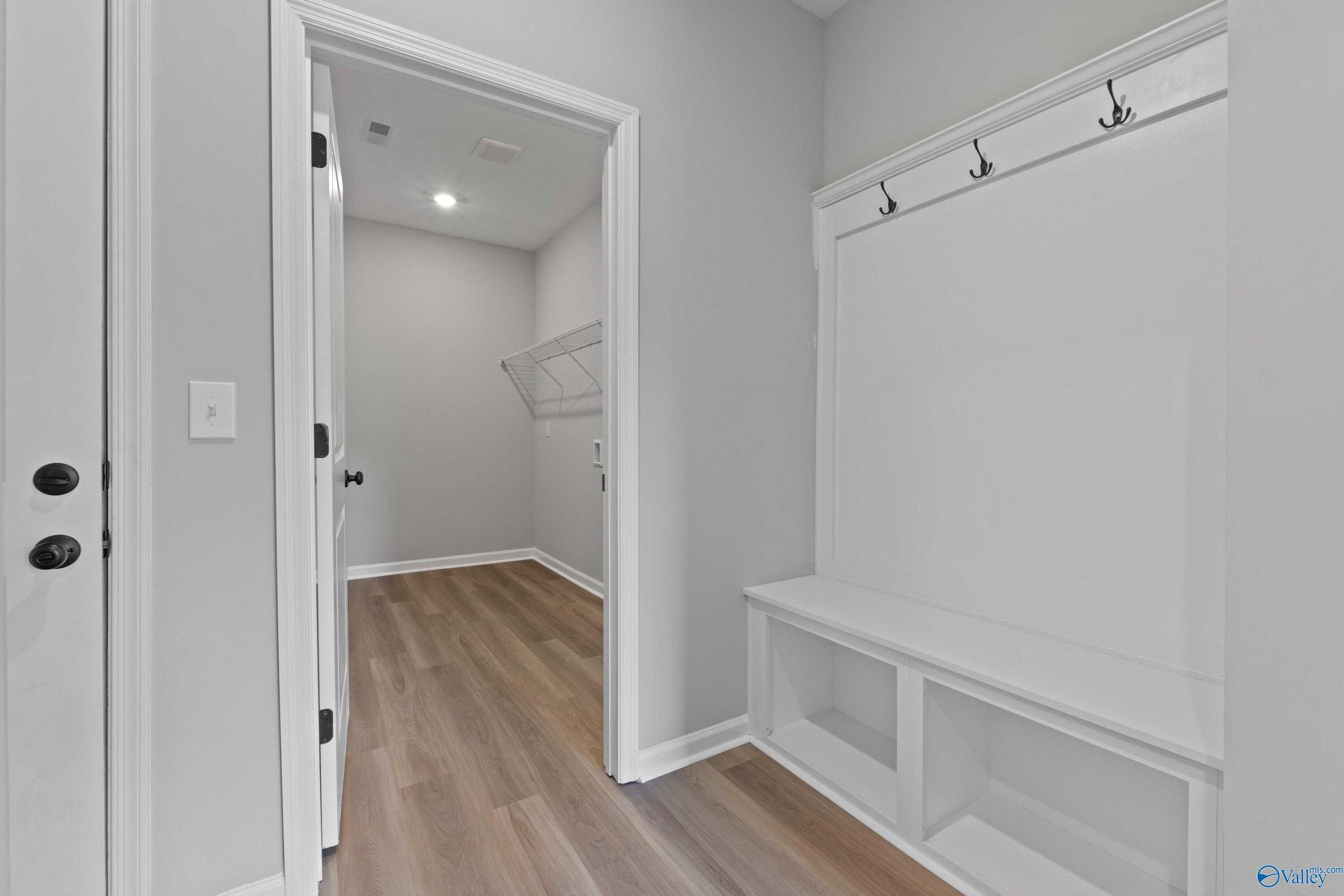 Functional mudroom with built-in bench, coat hooks, and hardwood floors in Davidson Homes The Dorado, Huntsville AL