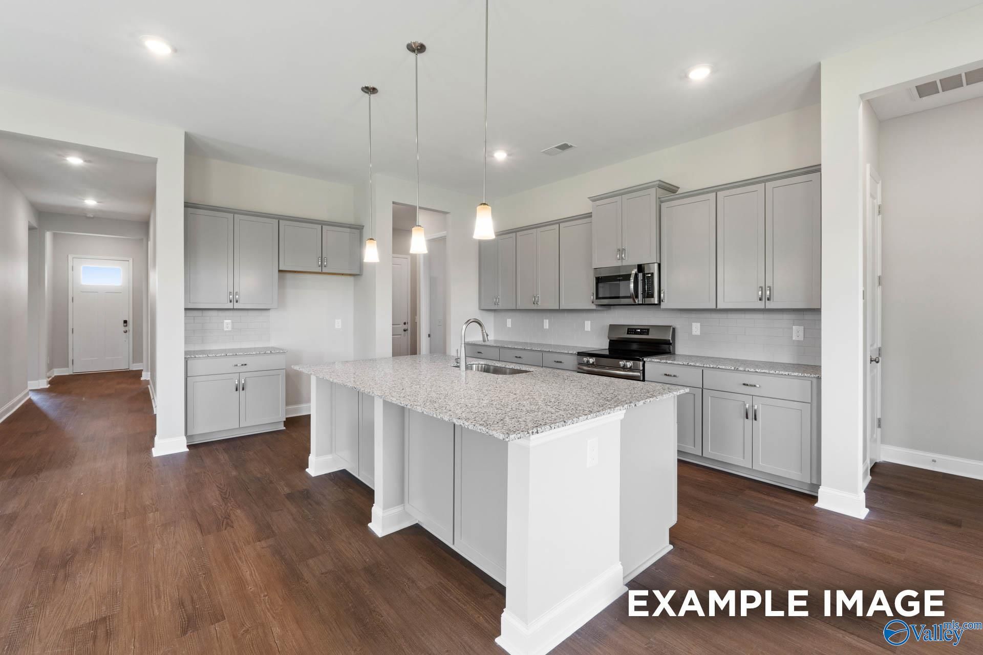 Modern kitchen featuring gray cabinets, granite island, stainless appliances in Evermore Homes The Arcadia, Owens Cross Roads, Alabama