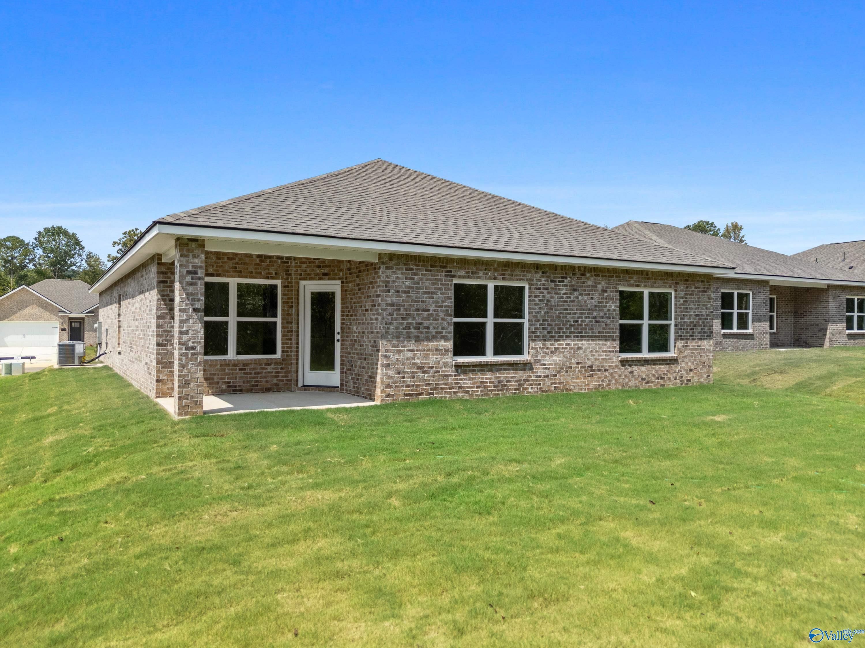 Single-story 4-bedroom brick home with covered porch, double windows, green lawn and blue sky in Spragins Cove, Huntsville, Alabama by Davidson Homes The Daphne