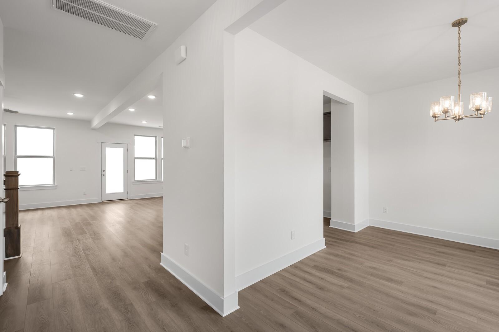 Spacious dining room with modern chandelier, hardwood floors, and open layout in Davidson Homes The Willow C, Gallatin, TN