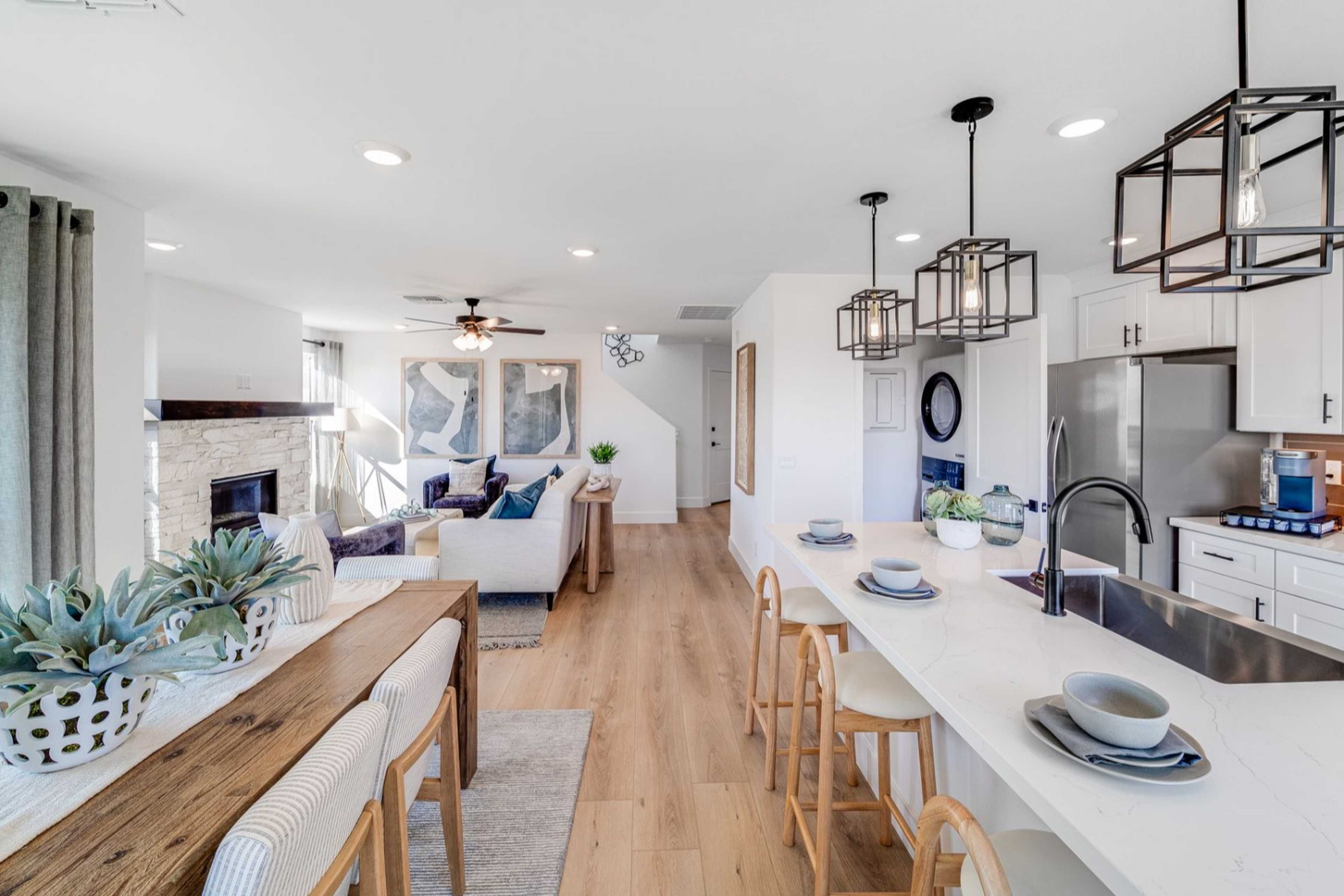 Open-concept kitchen and living room in The Wilmington B with white cabinets, large island, fireplace, and hardwood floors