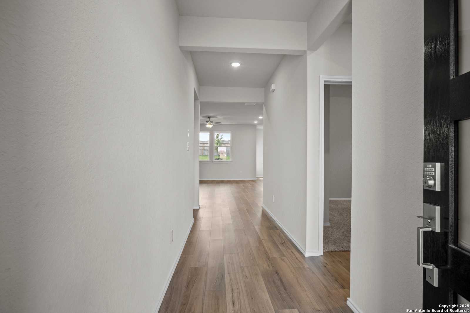 Bright hallway with light wood floors, recessed lights and ceiling fan in The Asheville J 3-bedroom home, San Antonio, Texas