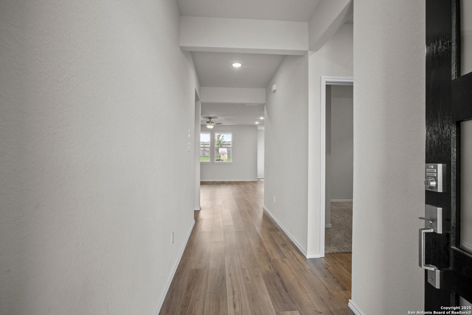 Bright hallway with light wood floors, recessed lights and ceiling fan in The Asheville J 3-bedroom home, San Antonio, Texas