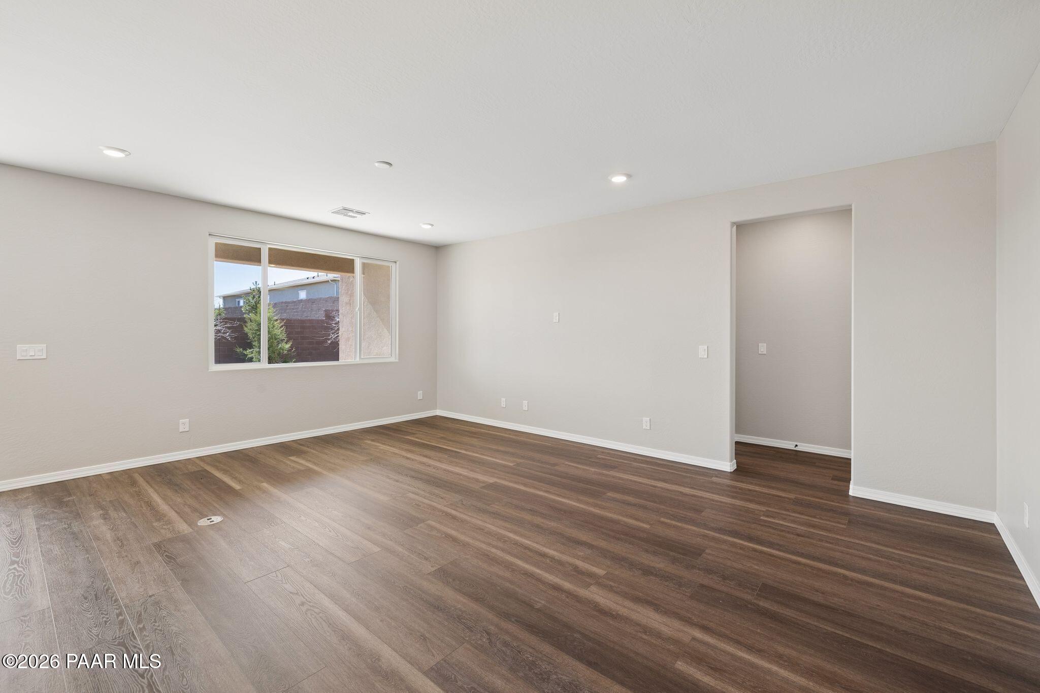 Spacious empty living room with beige walls, large window, hardwood floors in The Durango II B by Davidson Homes, Prescott AZ