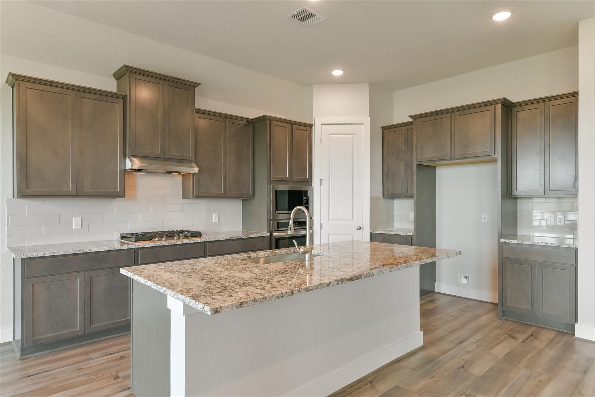 Modern kitchen with granite island, shaker cabinets, and stainless appliances in Davidson Homes The Edward A, Lago Mar, Texas