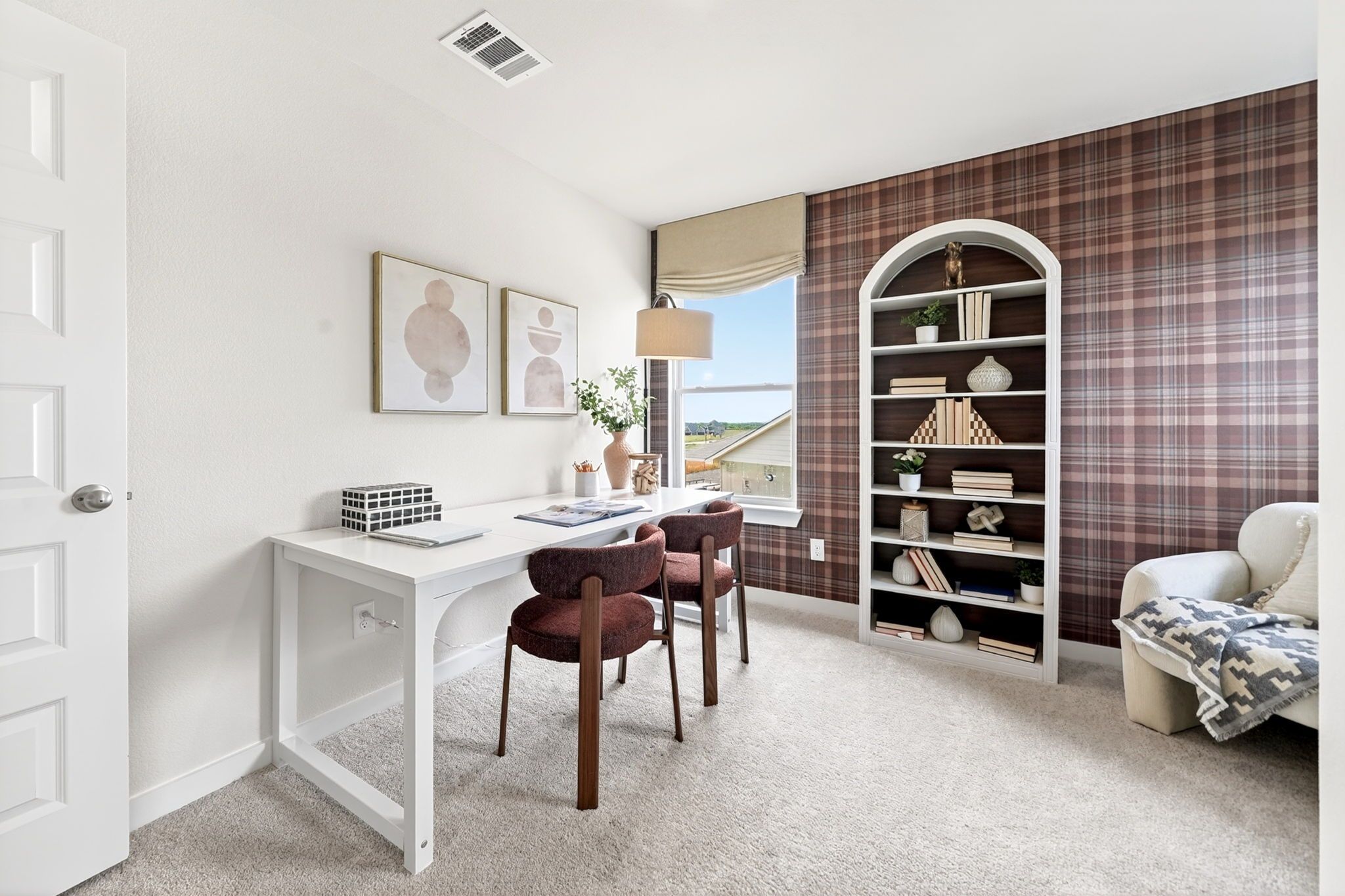 Cozy home office with white desk, maroon chairs, plaid wallpaper, arched bookshelf and window view in Heartland Texas by Davidson Homes