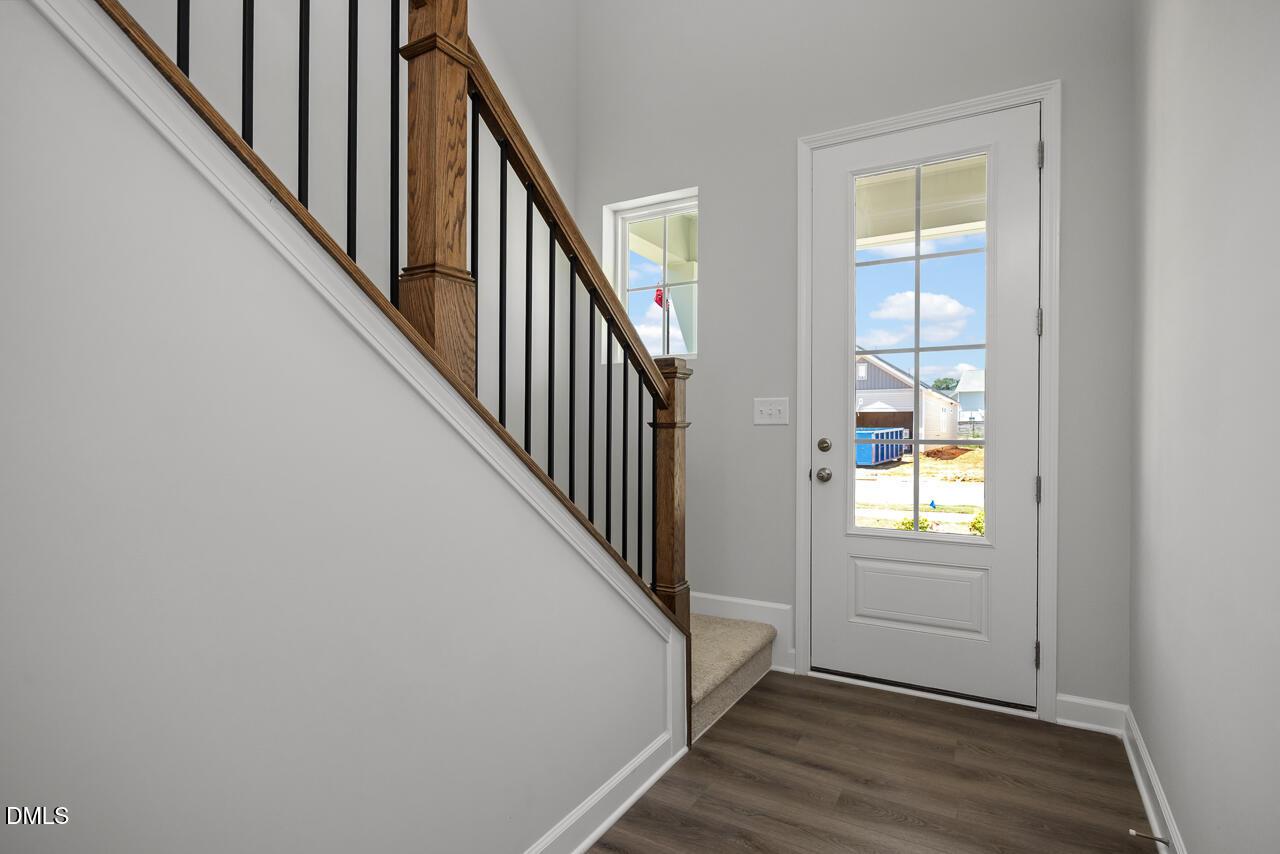Foyer entrance with wood stair railing and glass-paneled front door in The Adalynn A floor plan at Gregory Village.