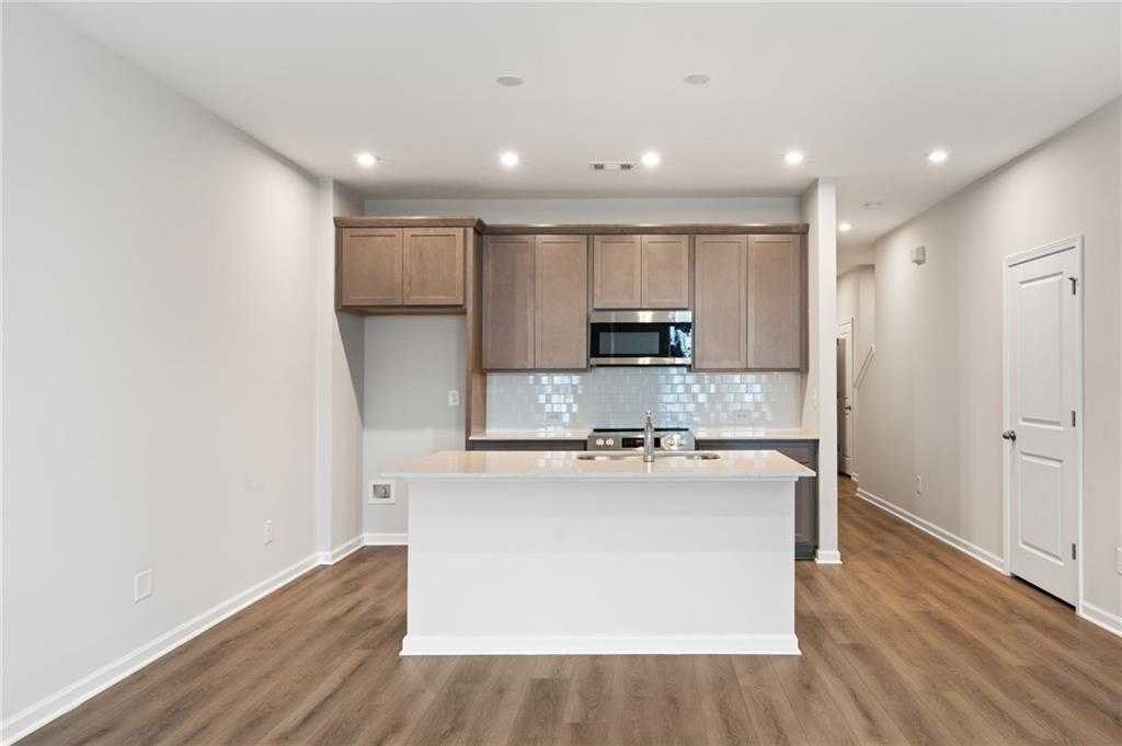 Modern open-concept kitchen with white island, stainless appliances, subway tile backsplash in Davidson Homes The Monroe A, Emerson, GA