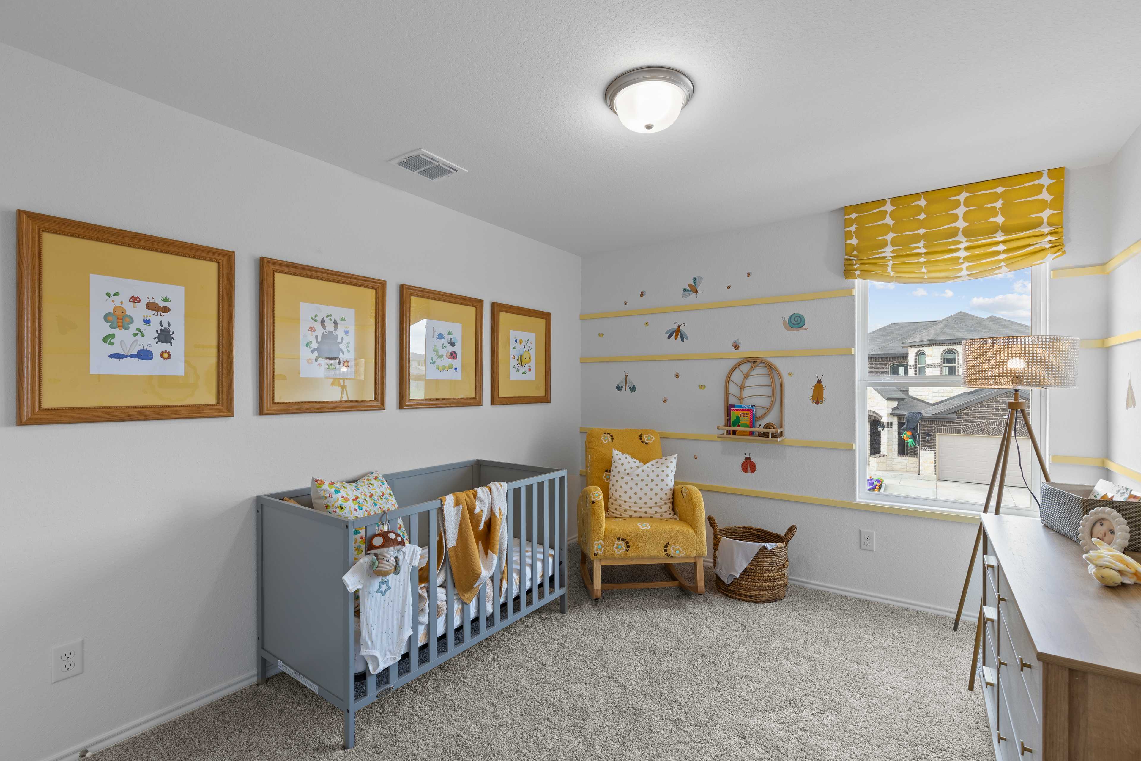 Cozy nursery with gray crib, yellow rocking chair, and framed sea art at Horizon Pointe in Converse, Texas by Davidson Homes