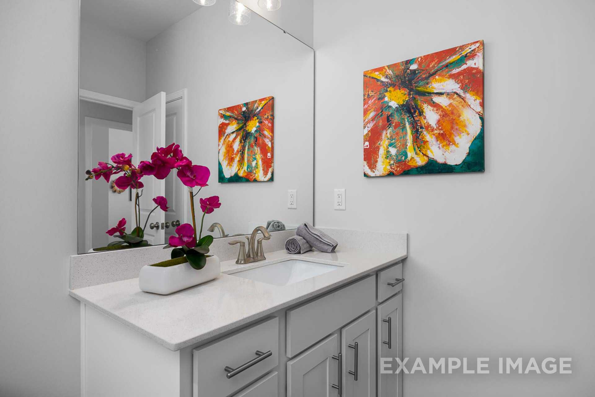 Modern master bathroom in The Carter B with white double vanity, quartz countertop, orchids, and abstract floral art