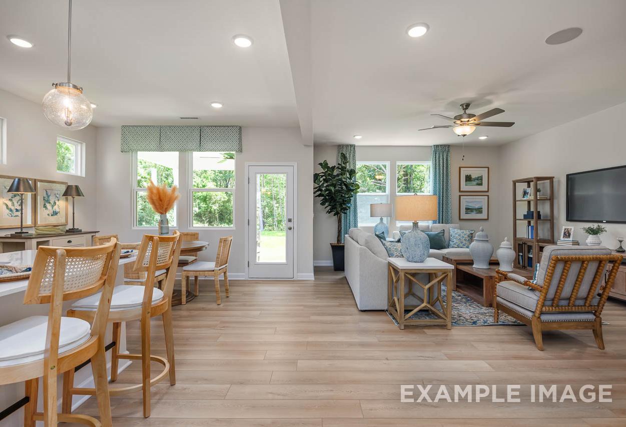 Open-concept living and dining area in The Willow C-BF by Davidson Homes, featuring hardwood floors and bright coastal decor.