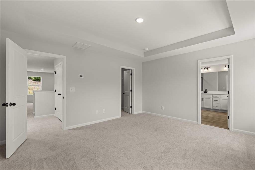 Spacious primary bedroom with tray ceiling and en-suite bathroom in The Hartwell A floor plan at The Bluffs, Canton, GA.