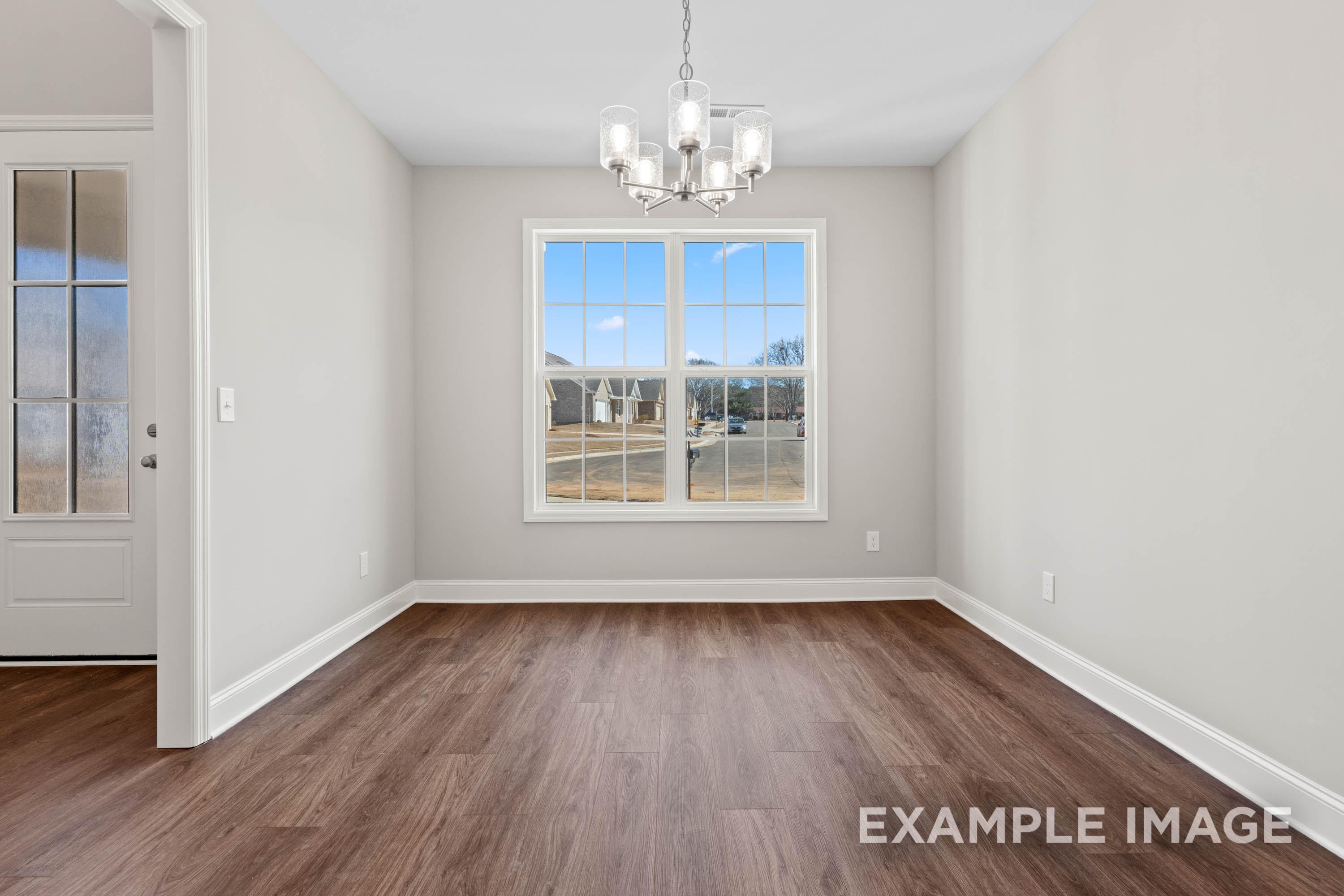 Spacious dining room in The Madison B home with light gray walls, large window, chandelier, and hardwood floors