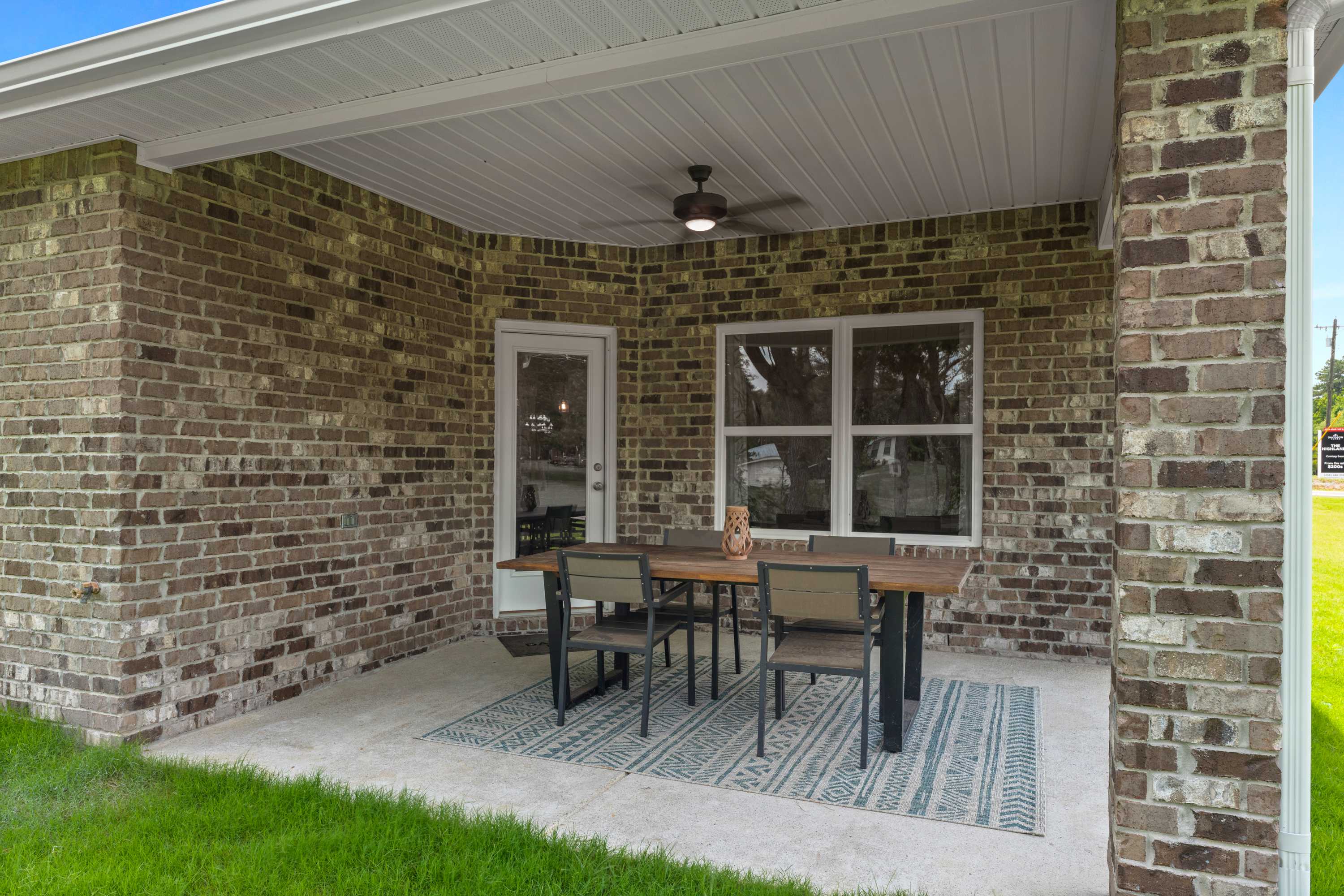 Covered patio at The Highlands in Arab, Alabama with brick walls, ceiling fan, French doors, and outdoor dining furniture